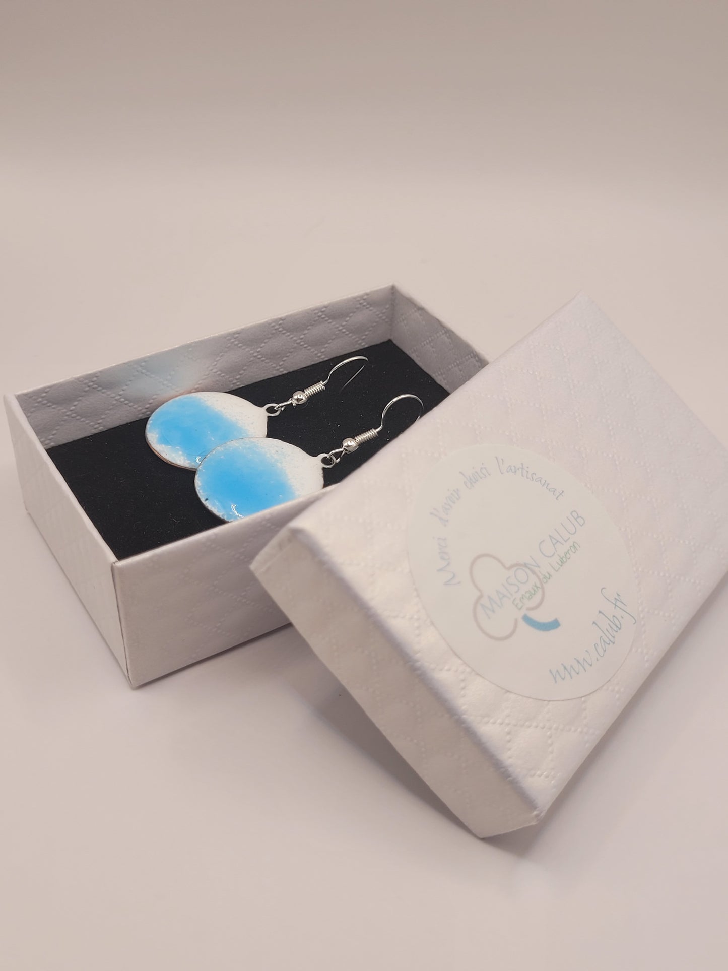 dans leur boite cadeau les boucles d'oreilles rondes oh bleu de maison calub pendant en émail sur cuivre bleu translucide sur fond blanc émaux traditionnels