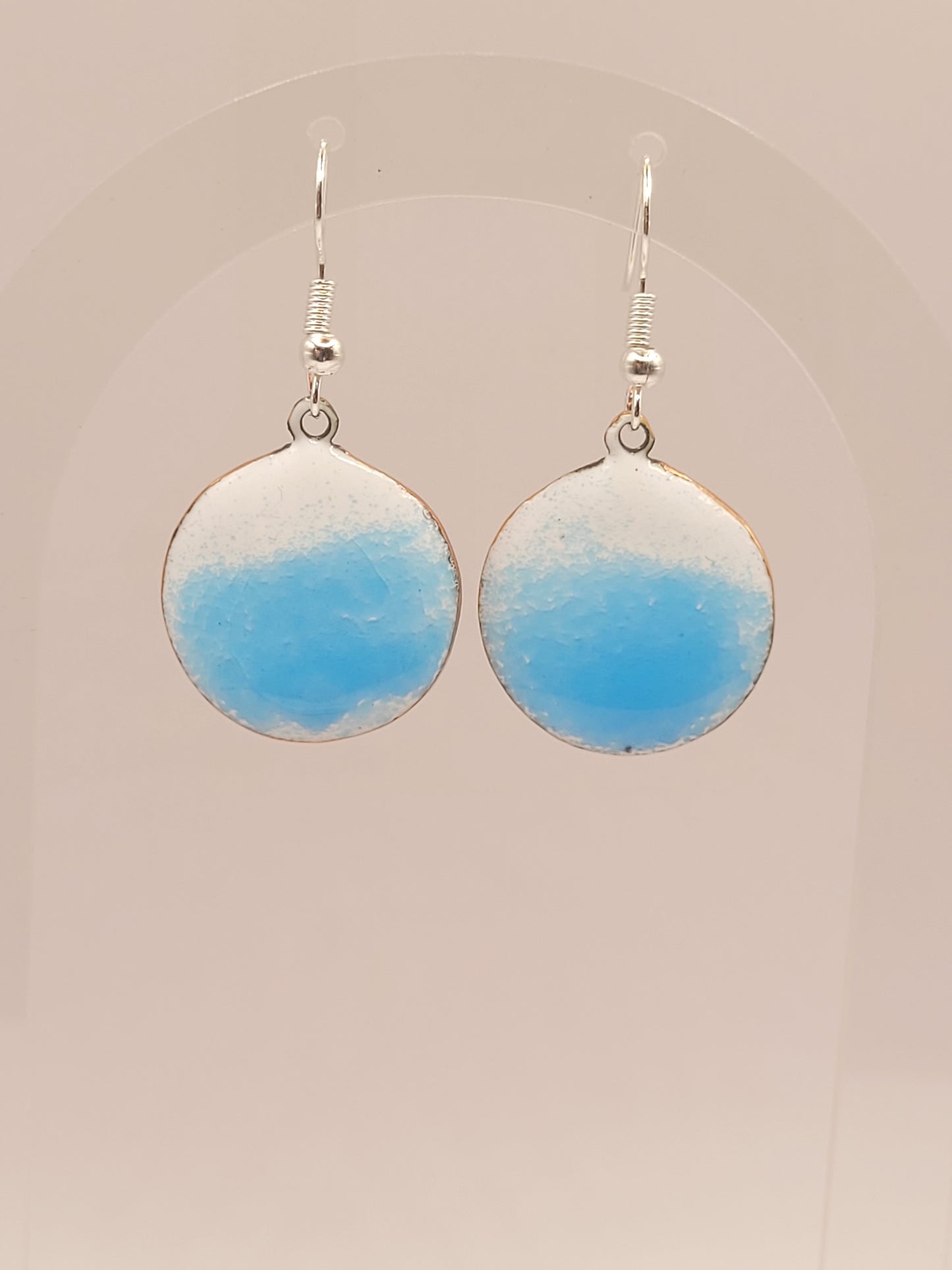 sur un présentoir les boucles d'oreilles rondes oh bleu de maison calub pendant en émail sur cuivre bleu translucide sur fond blanc émaux traditionnels