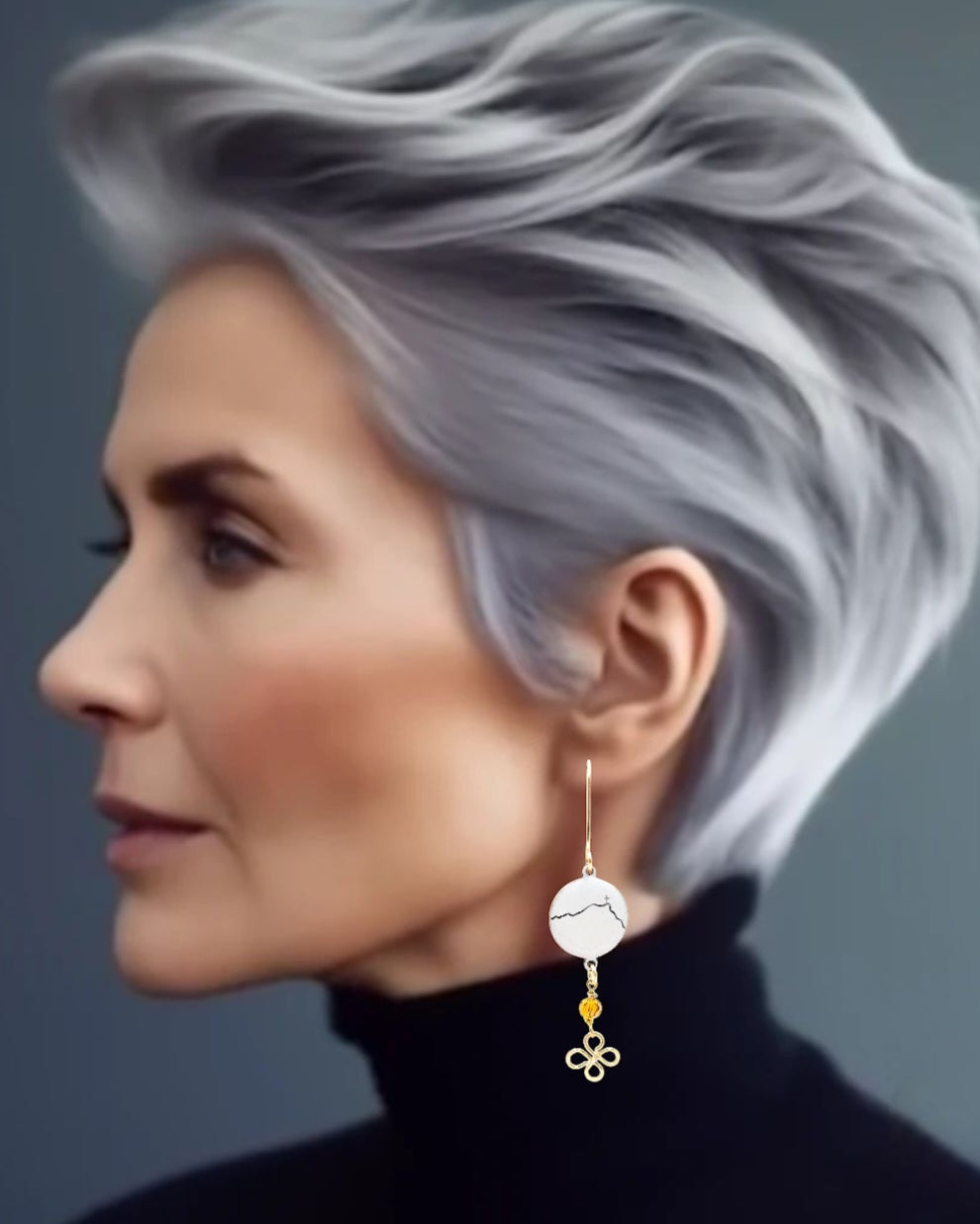 femme cinquantaine portant une bijou maison Calub. Ici se sont des boucles d'oreilles Sainte Victoire dorées en émail sur cuivre - bijou artisanal français évoquant la silhouette de la montagne sainte victoire à Aix-en-Provence, d'une simple ligne noire sur fond blanc. Breloque dorée et perle de verre ambrée.