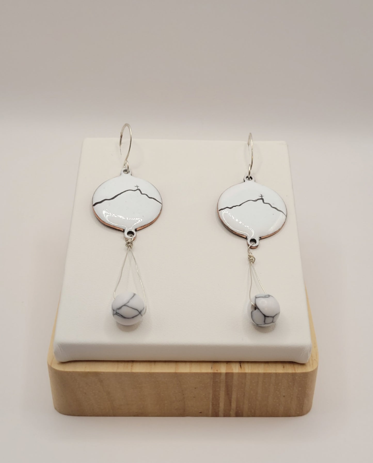 boucles d'oreilles en émail sur cuivre blanche, ornées de la ligne noire évoquant la montagne sainte-victoire à Aix en Provence. Création maison Calub.