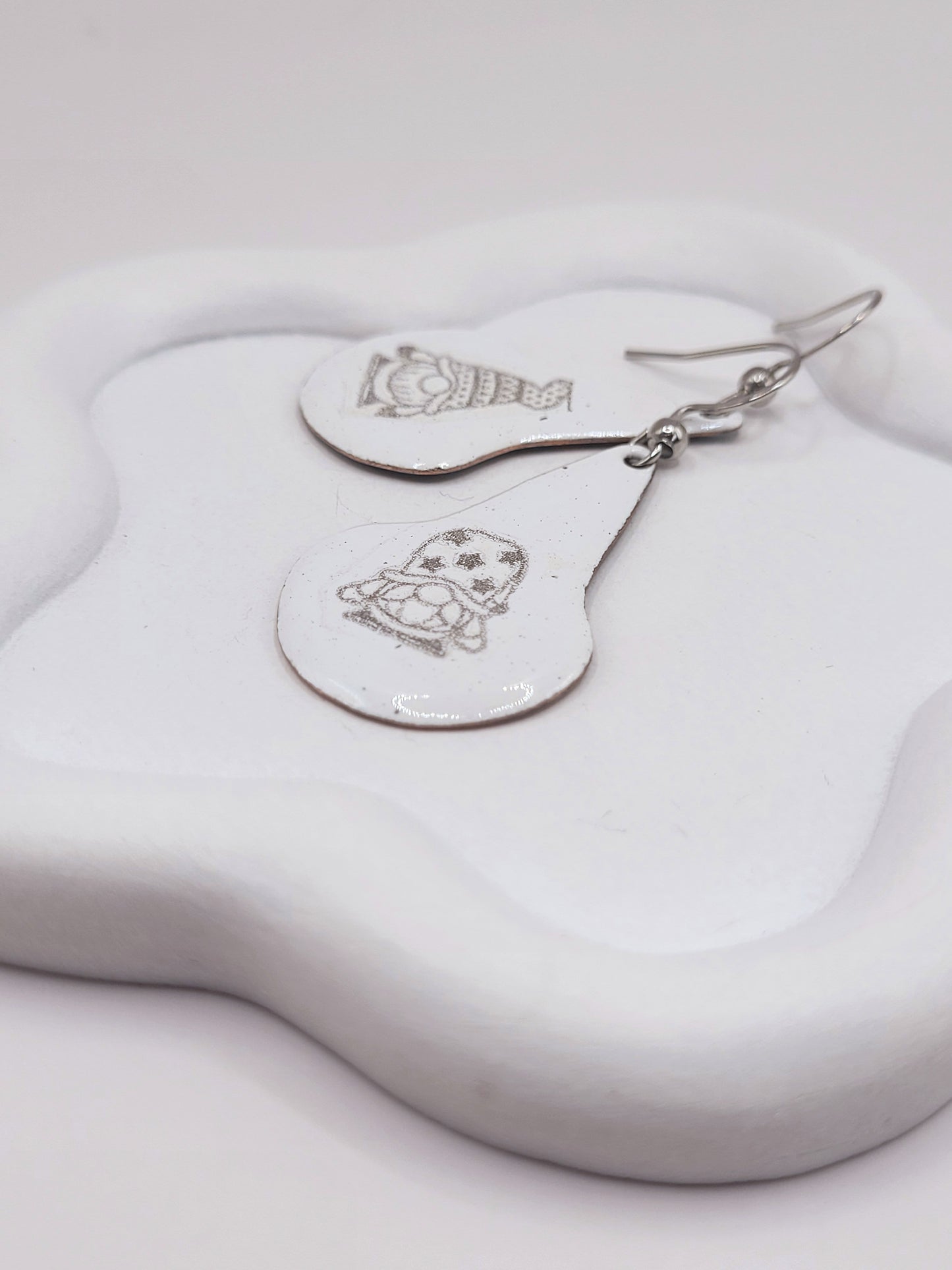 gros plan sur boucles d'oreilles en email sur cuivre en forme de goutte avec un petit personnage mignon noir sur fond blanc maison calub