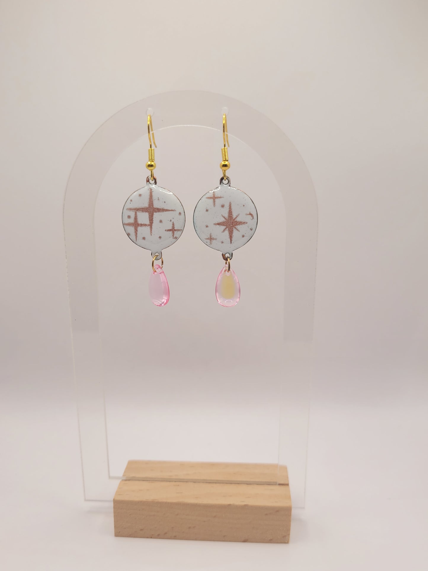 boucles d'oreilles en émail sur cuivre aux motif d'étoiles rosés sur blanc prolongé par une perle de verre goutte. Bijou artisanal fait à la main chez maison calub les emaux du Luberon