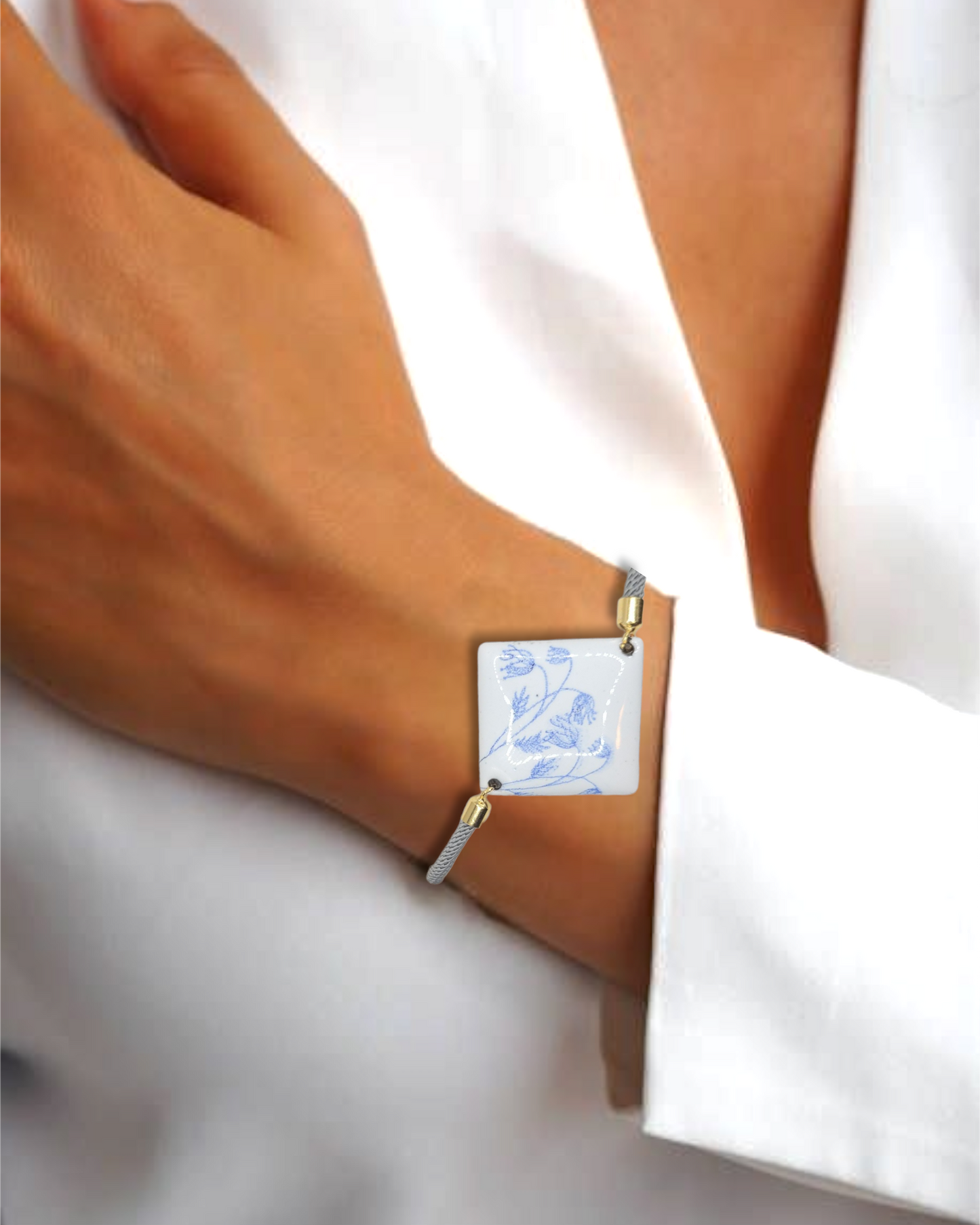 Bracelet cordon gris en émail sur cuivre de forme carrée. Les motifs bleus sur un émail blanc porcelaine dans la collection Les Uniques chez Maison Calub.