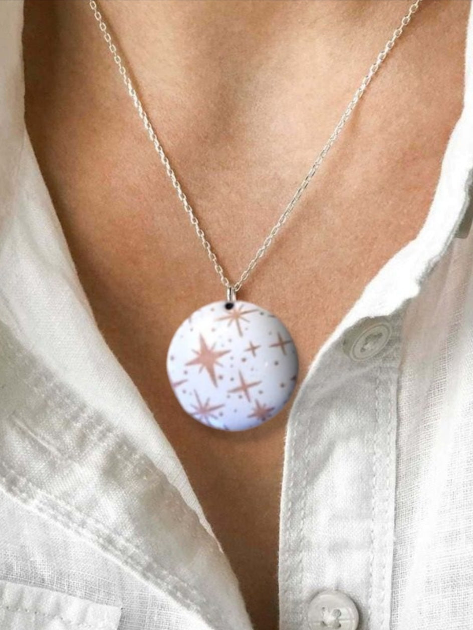 decolleté avec pendentif émaillé lumineux aux fines étoiles rosées sur fond blanc émaux sur cuivre artisanaux de maison calub