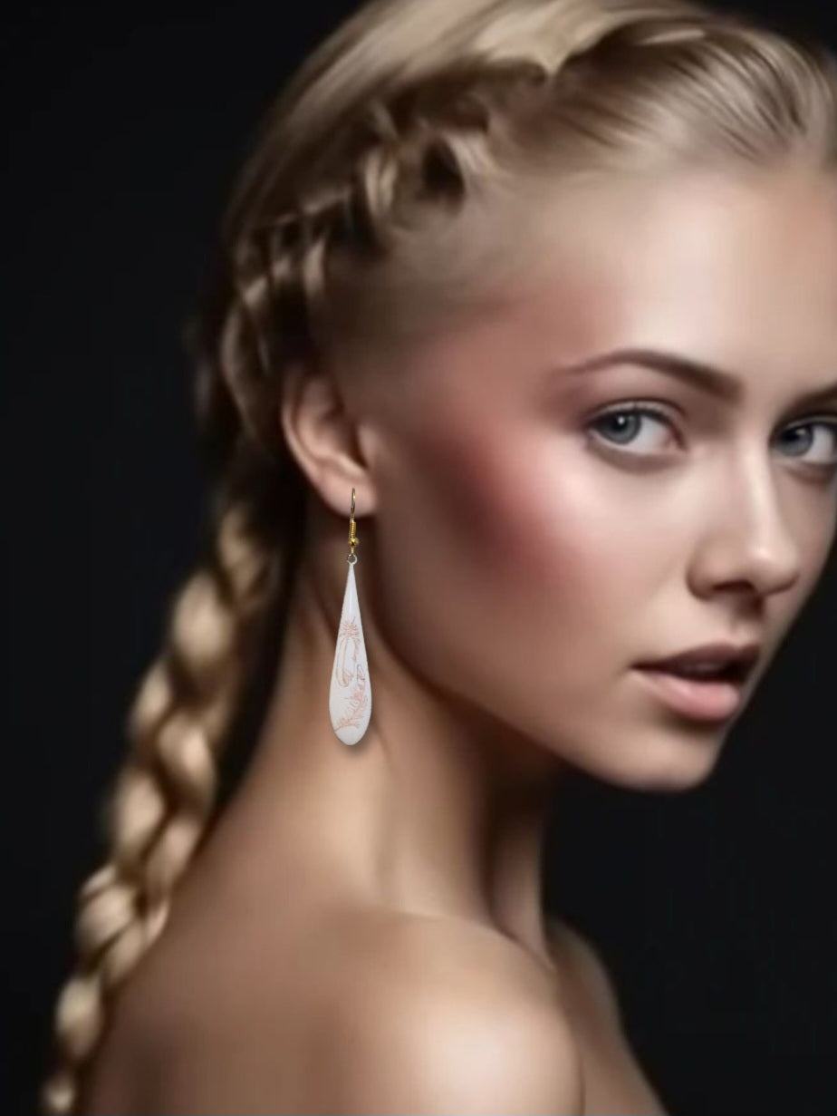 jeune femme portant les boucles d'oreilles gouttes longues en émail sur cuivre aux motifs très fin de plumes . Bijou artisanal maison calub les émaux du Luberon