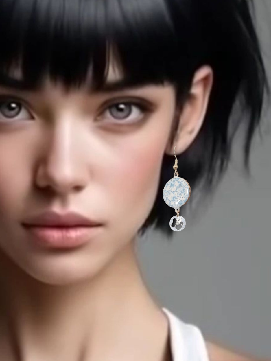 jeune femme portant les boucles d'oreilles en email sur cuivre aux motifs floraux légers hibiscus bleus prolongé par une breloque en argent hibiscus. Bijou artisanal émaillé à la main chez maison CALUB les émaux du Luberon