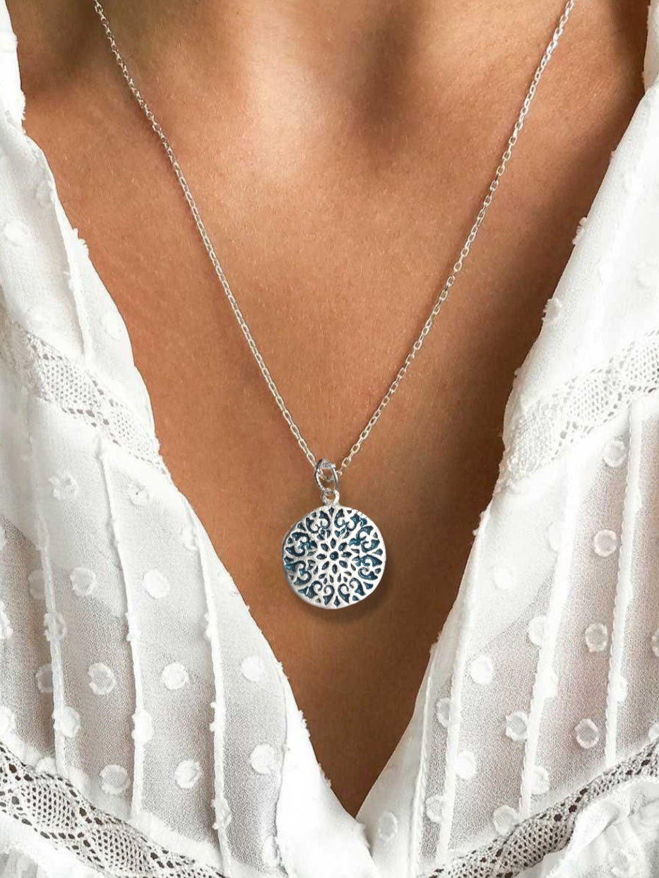 decolleté avec petit pendentif discret en forme de rosace en email sur argent fin bleu. Emaux translucide bijou artisanal réalisé à la main atelier maison calub les émaux du Lubero en Provence made in France