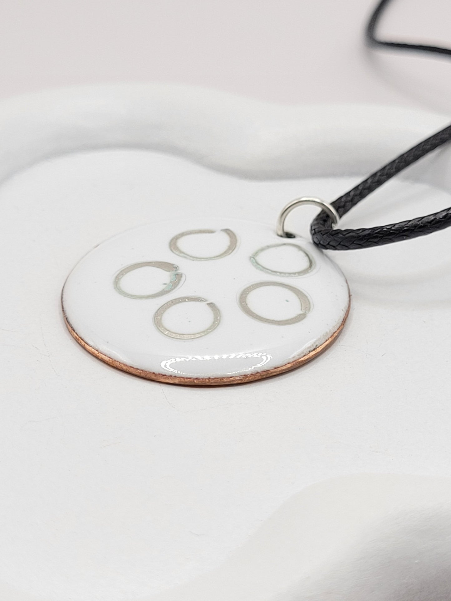 gros plan sur le pendentif rond en email sur cuivre avec des anneaux en argent incrustés chez maison calub design contemporain
