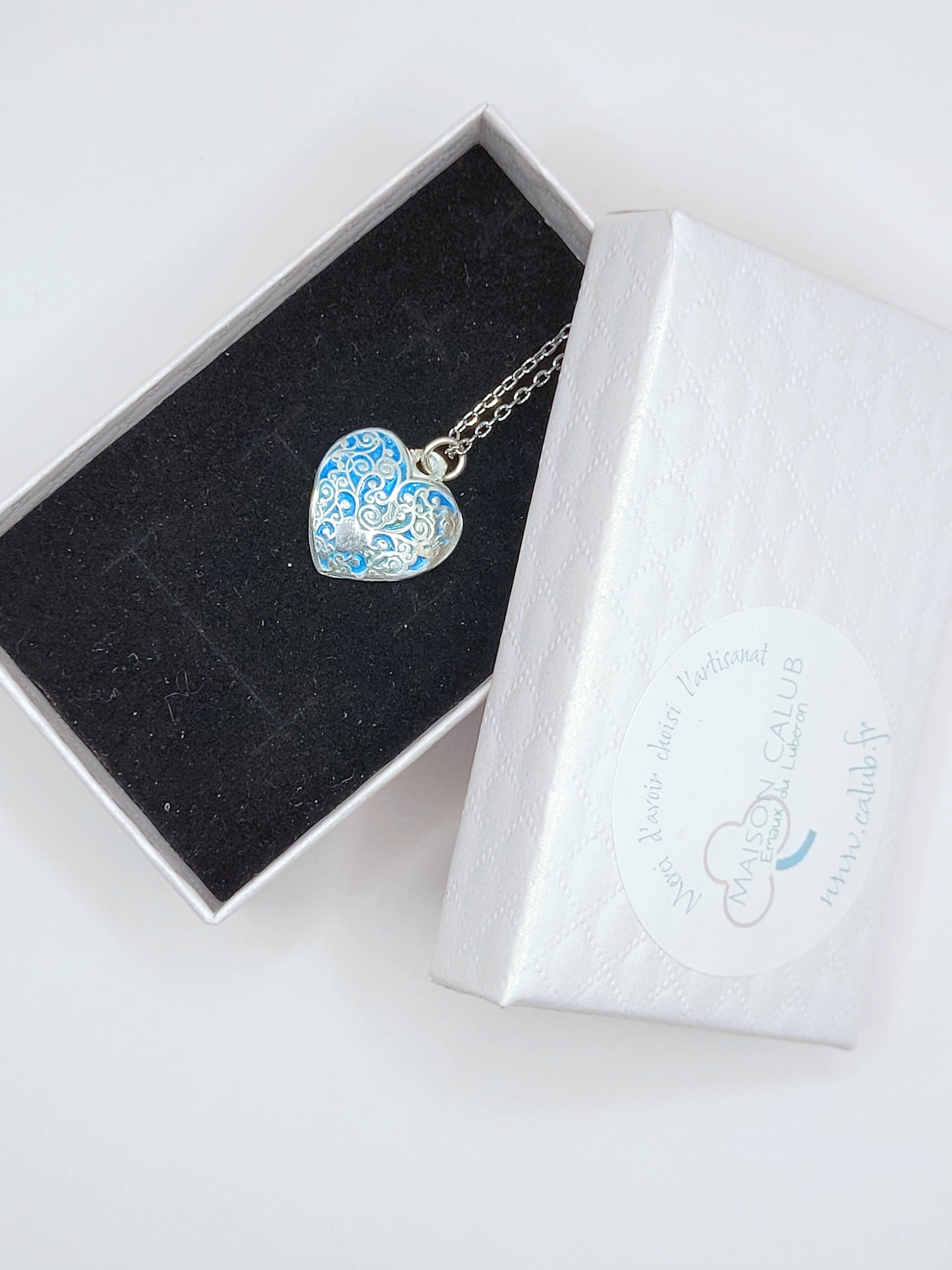 dans sa boite cadeau le petit pendentif en émail sur argent fin légèrement bombé champelevé et émaux bleus. Bijou artisanal réalisé à la main dans l'ateiler maison calub les émaux du Luberon