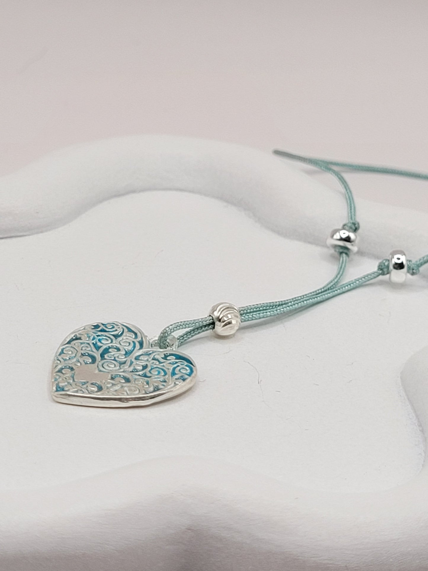 gros plan sur petit pendentif en émail sur argent fin champelevé et émaux bleus. Bijou artisanal réalisé à la main dans l'ateiler maison calub les émaux du Luberon
