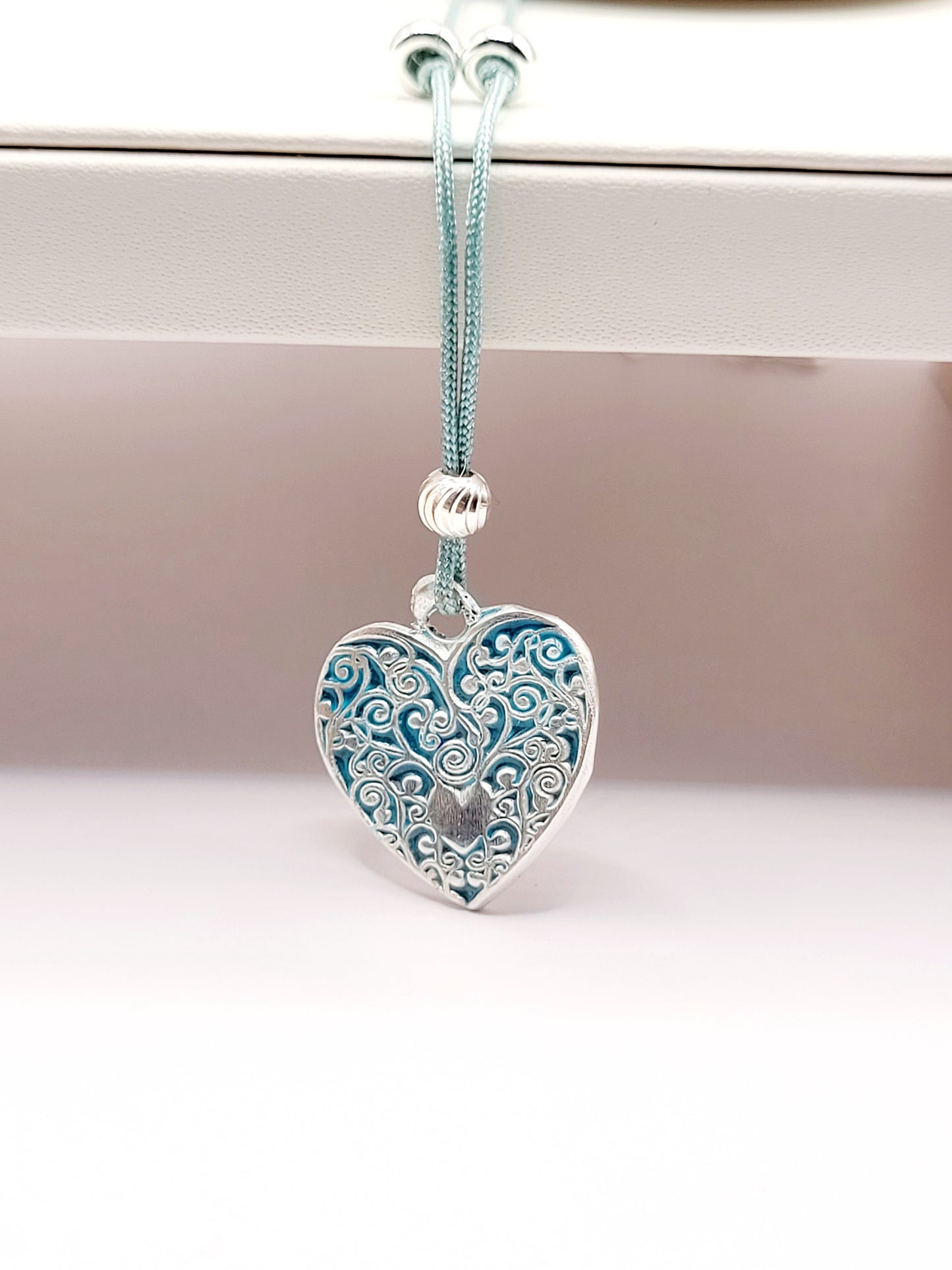 présentation du petit pendentif en émail sur argent fin champelevé et émaux bleus. Bijou artisanal réalisé à la main dans l'ateiler maison calub les émaux du Luberon