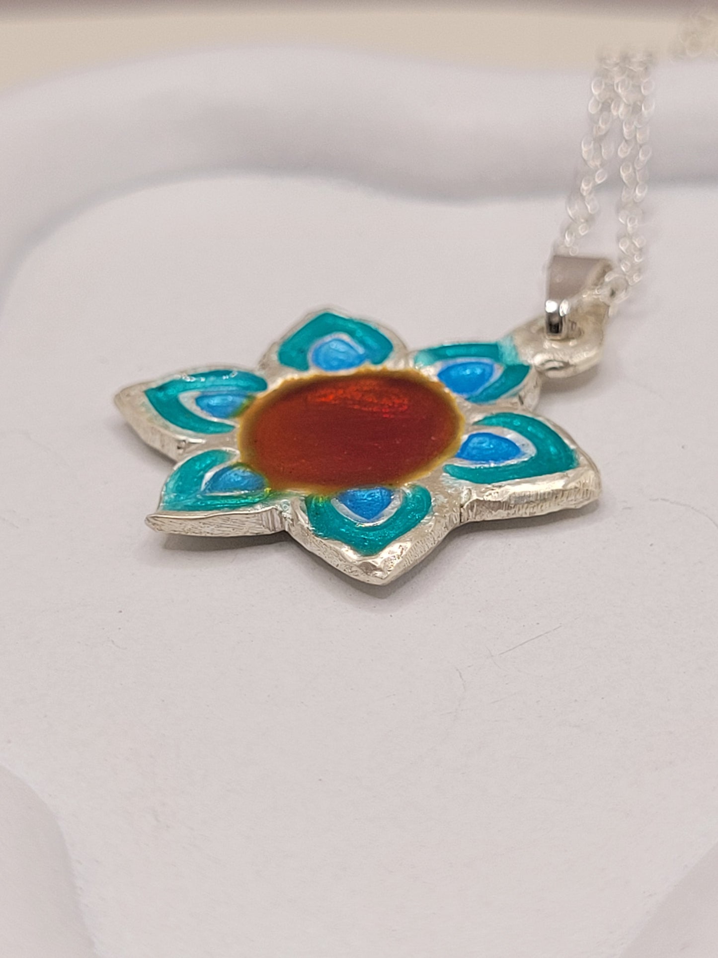 gros plan sur le pendentif fleur champlevé en émail sur argent fin multicolore. Bijou artisanal fait main chez maison calub les émaux du Luberon