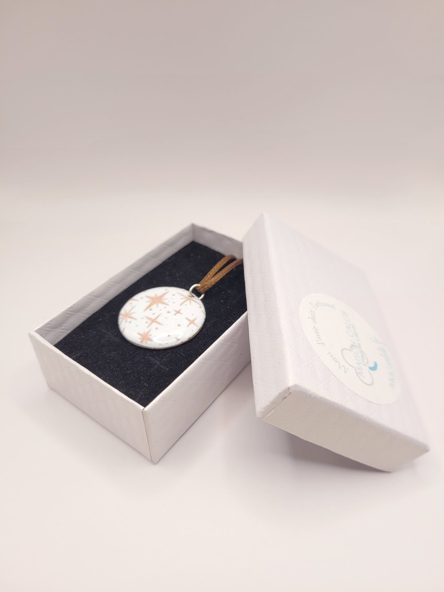 pendentif émaillé lumineux aux fines étoiles rosées sur fond blanc émaux sur cuivre artisanaux de maison calub dans sa boite cadeau