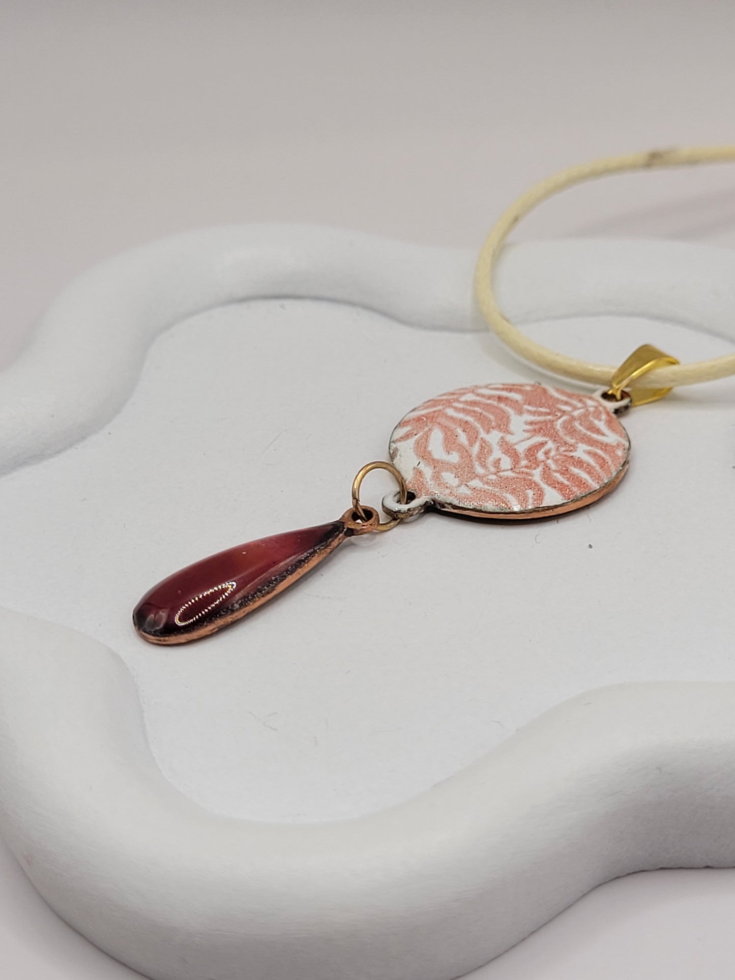 gros plan sur le pendentif double rouge rubis emaux translucide cuivre monté sur cordon, bijou en email de maison calub