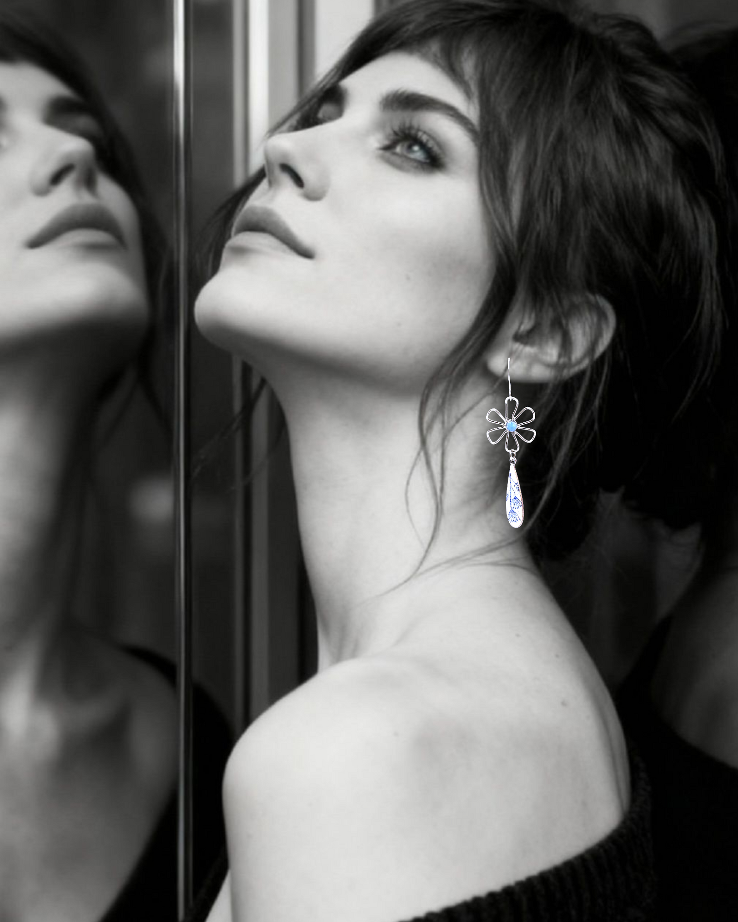 femme protant les boucles d'oreilles effet porcelaine bijou artisanal fait main, boucles d'oreilles pendantes en émail sur cuivre et argent, aux allure de porcelaine aux motif floraux bleus. Création originale Maison calub