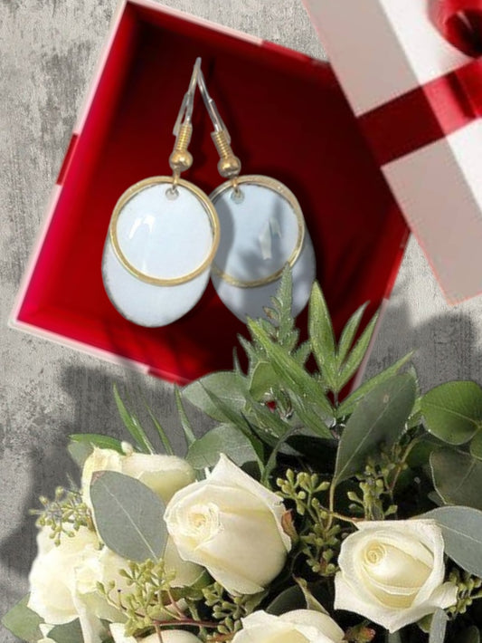 dans un boite cadeau des boucles d'oreilles blanches en émail avec un anneau doré. Emaux traditionnels fait main chez maison calub. Bijou artisanal