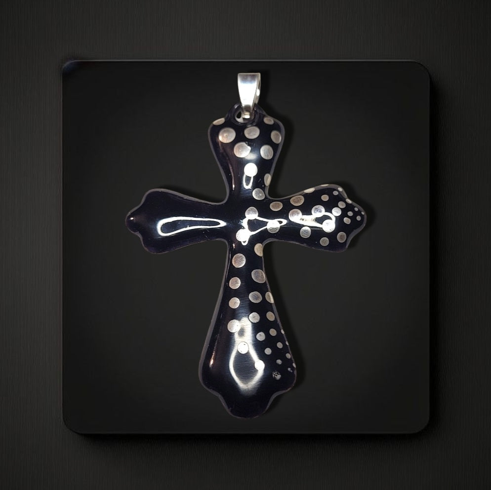 sur fond noir un pendentif croix émaillée en forme de croix et aux petits pois d'argent . Bijou artisanal maison calub