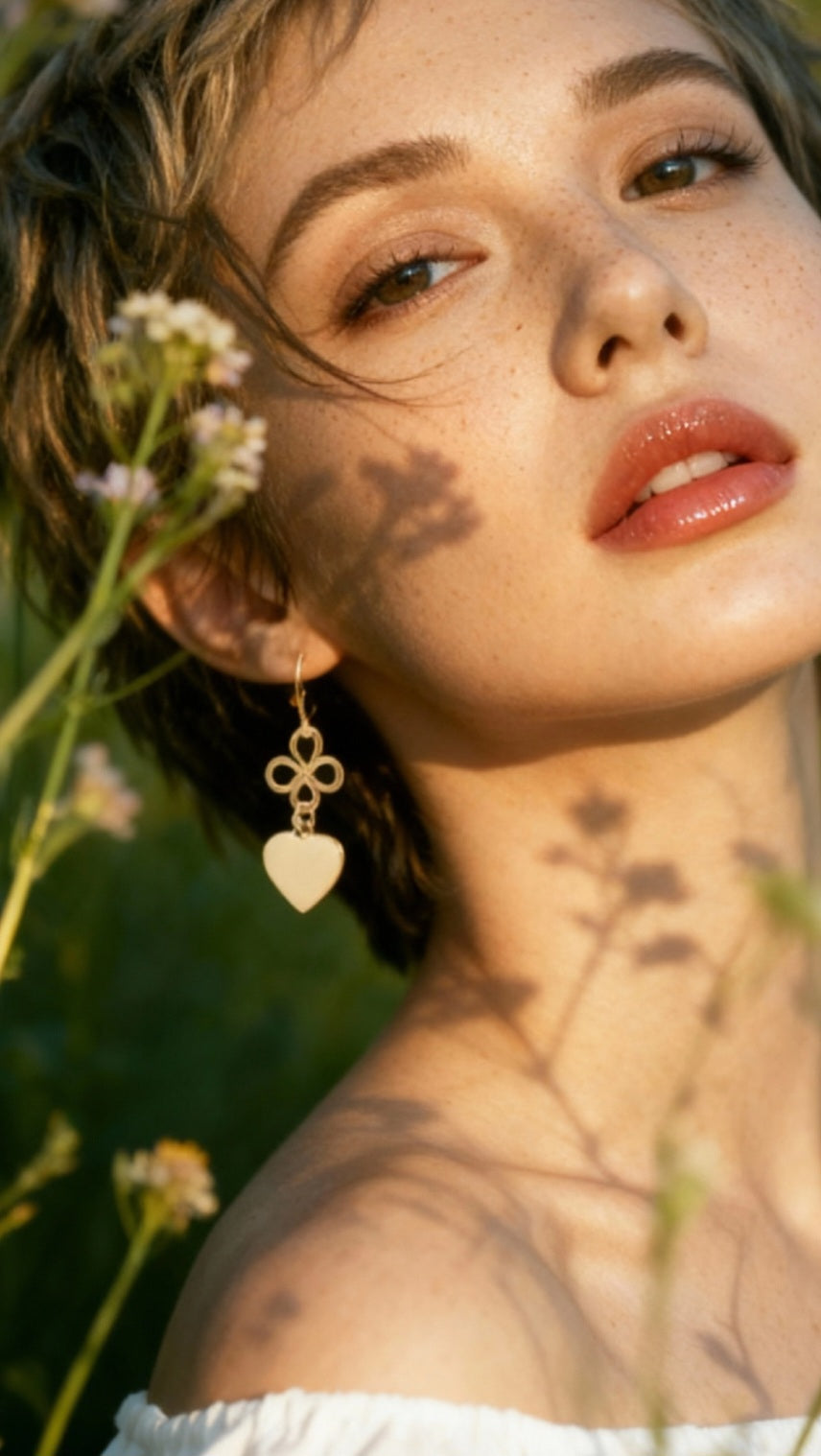 femme portant un bijou artisanal fait main, boucles d'oreilles coeur en émail  blanc montage sur laiton doré. Création artisanale de maison calub. Emaux opaques