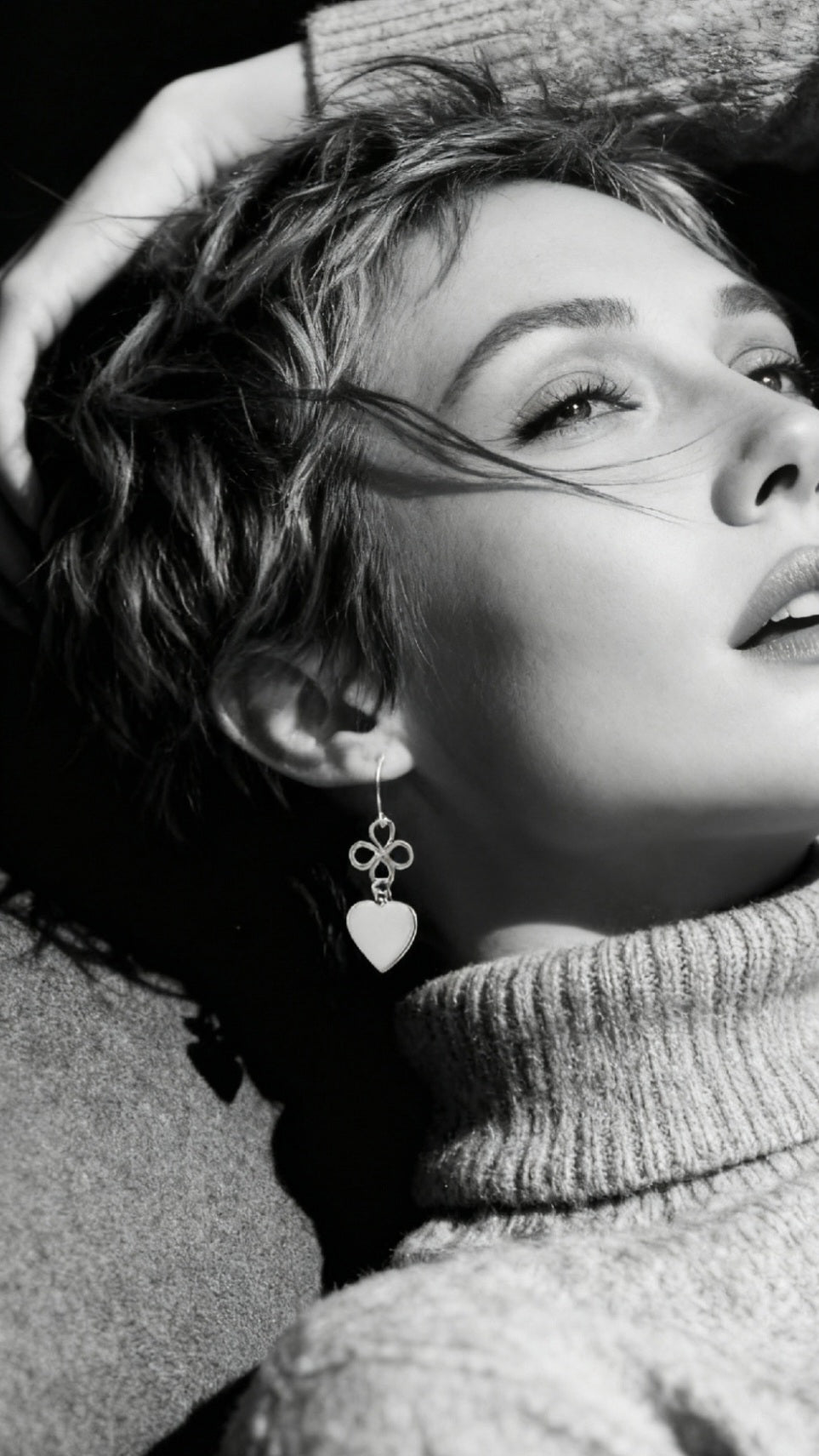 femme portant un bijou artisanal fait main, boucles d'oreilles coeur en émail  blanc montage sur argent. Création artisanale de maison calub. Emaux opaques