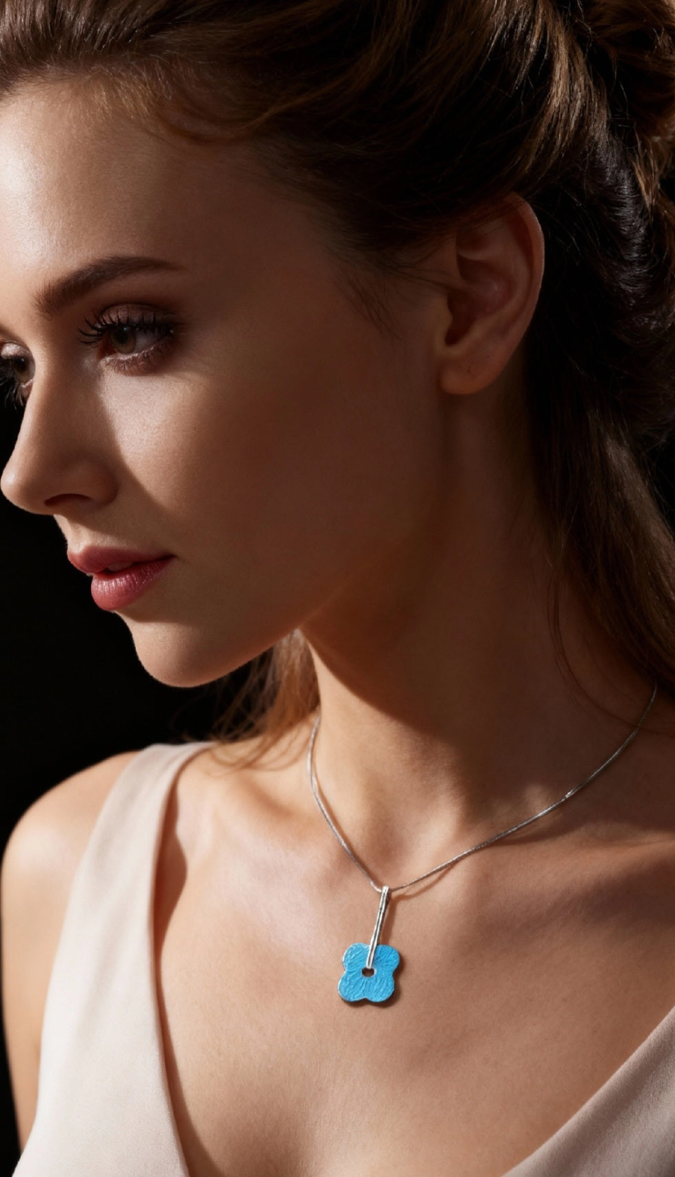 femme portant un pendentif fleur bleu en email grand feu basse-taille sur argent fin -maison CALUB - monté sur une chaine fine en argent. Création artisanale