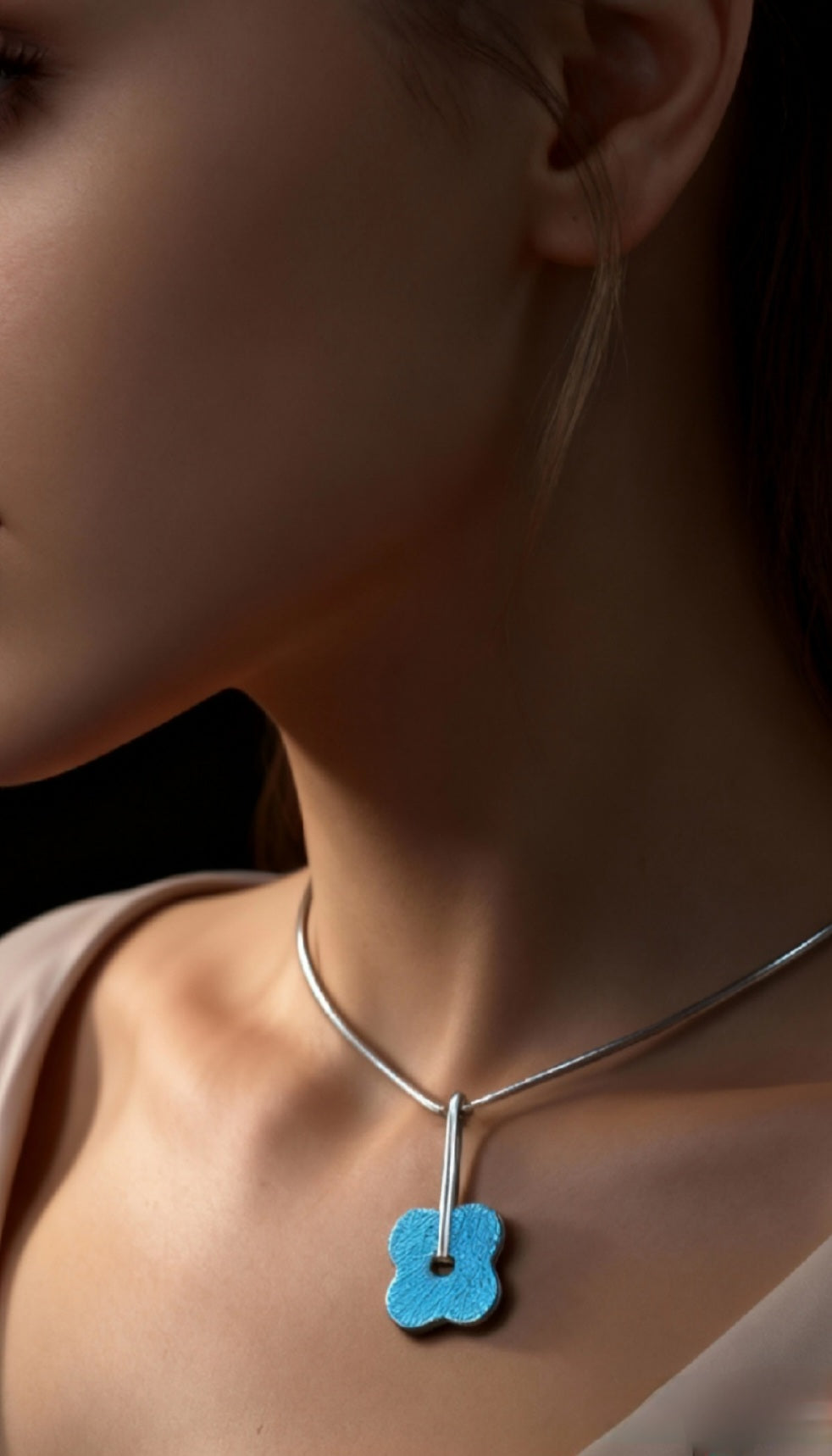 femme portant un pendentif fleur bleu en email grand feu basse-taille sur argent fin -maison CALUB - monté sur une chaine fine en argent. Création artisanale