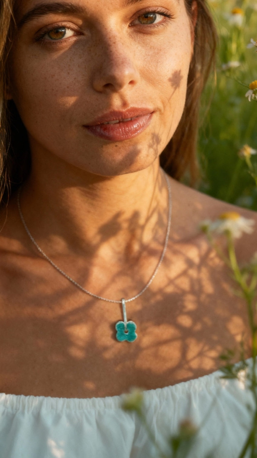 femme portant un pendentif fleur bleu en email grand feu basse-taille sur argent fin -maison CALUB - monté sur une chaine fine en argent. Création artisanale