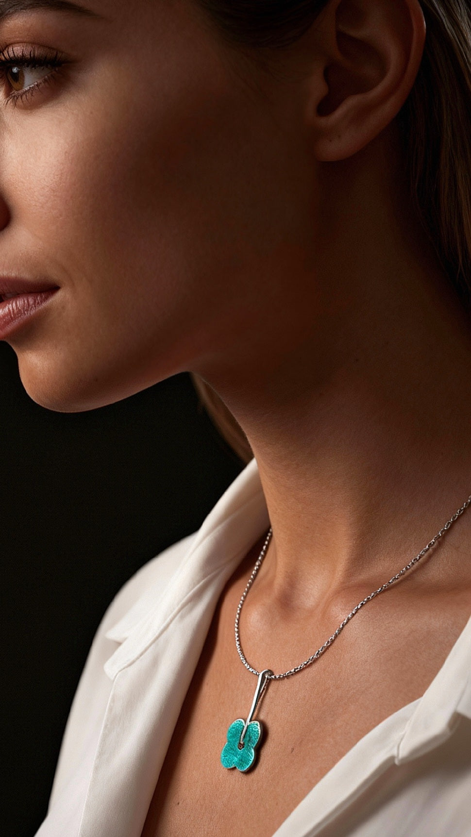 femme portant un pendentif fleur bleu en email grand feu basse-taille sur argent fin -maison CALUB - monté sur une chaine fine en argent. Création artisanale