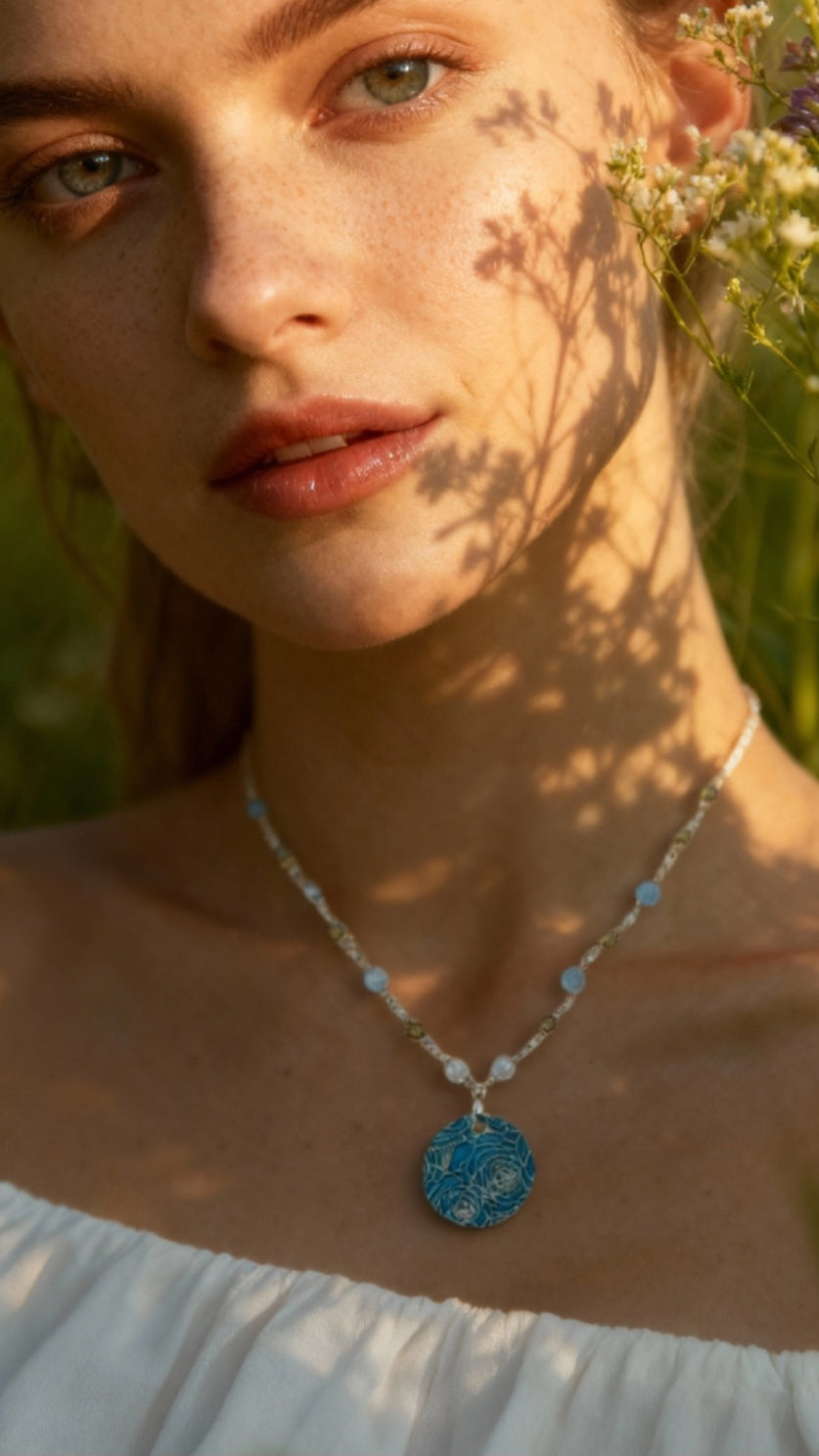 femme portant un pendentif bouquet de roses en champlevé émail sur argent fin avec rimbambelle de petites pierres naturelles et fine chaine argent. Bijou artisanal made in France chez maison calub les émaux du Luberon cadeau original