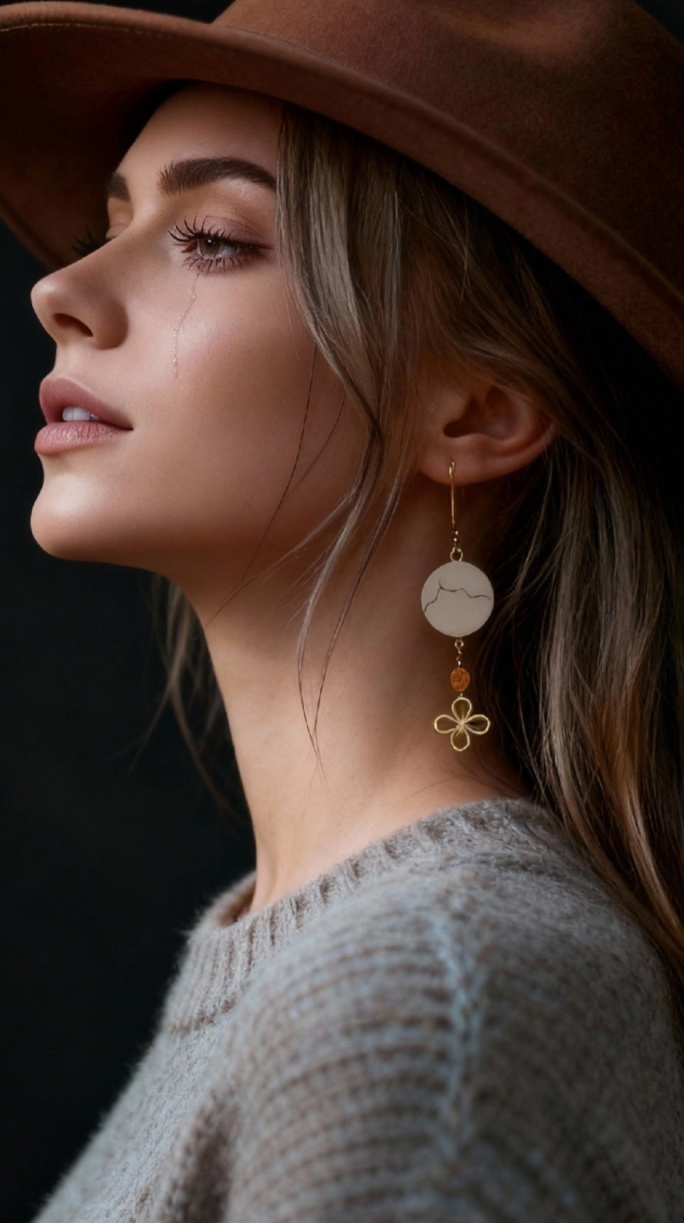 jeune femme portant les boucles d'oreilles en émail sur cuivre - bijou artisanal français évoquant la silhouette de la montagne sainte victoire à Aix-en-Provence, d'une simple ligne noire sur fond blanc.Breloque dorée et perle en verre