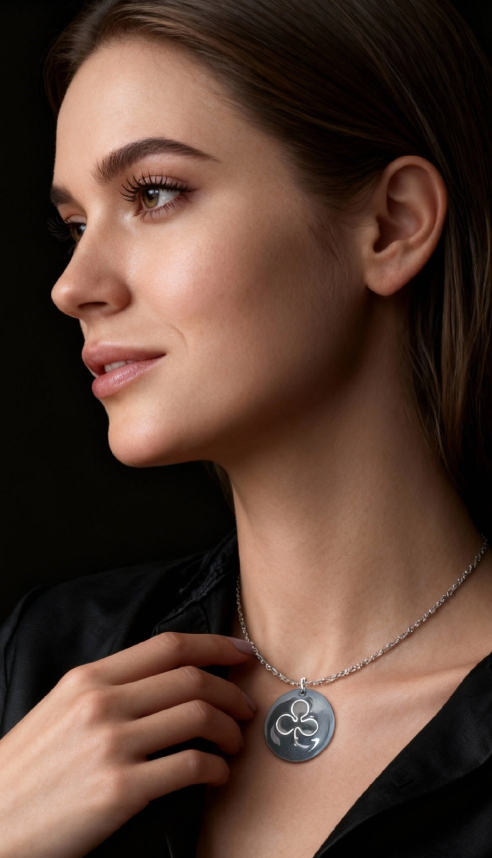 une jolie jeune femme porte le pendentif en email sur cuivre emblème de maison calub simple trèfle en argent fin sur émaux crème effet céramique. Création artisanale