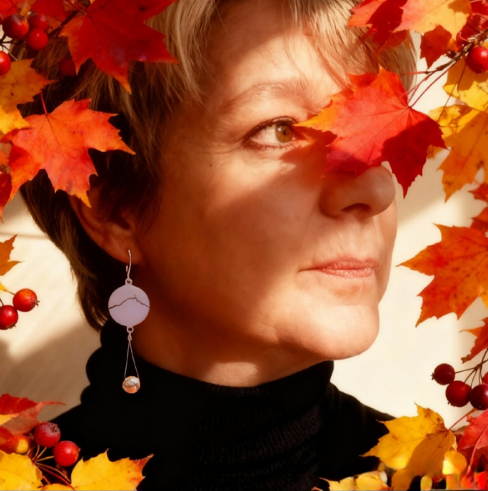 Boucles d'oreilles artisanales . femme portant les boucles d'oreilles en émail sur cuivre blanche, ornées de la ligne noire évoquant la montagne sainte-victoire à Aix en Provence. Création maison Calub. Bijou artisanal