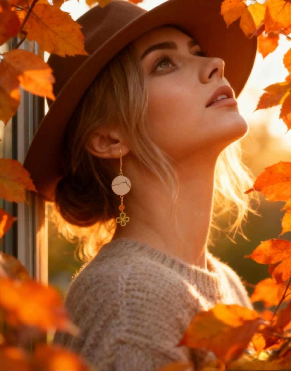 jeune femme portant les boucles d'oreilles en émail sur cuivre - bijou artisanal français évoquant la silhouette de la montagne sainte victoire à Aix-en-Provence, d'une simple ligne noire sur fond blanc.Breloque dorée et perle en verre