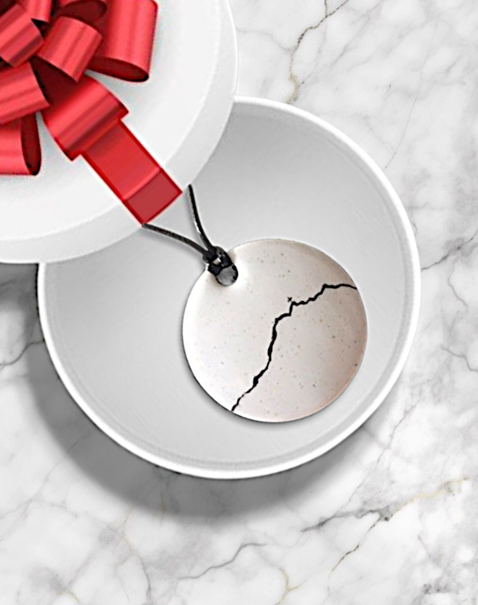 bijou artisanal fait main, grand pendentif en émail blanc avec une ligne noire représentant le profil de la montagne Sainte-Victoire. Création originale Maison calub. Dans une boite cadeau