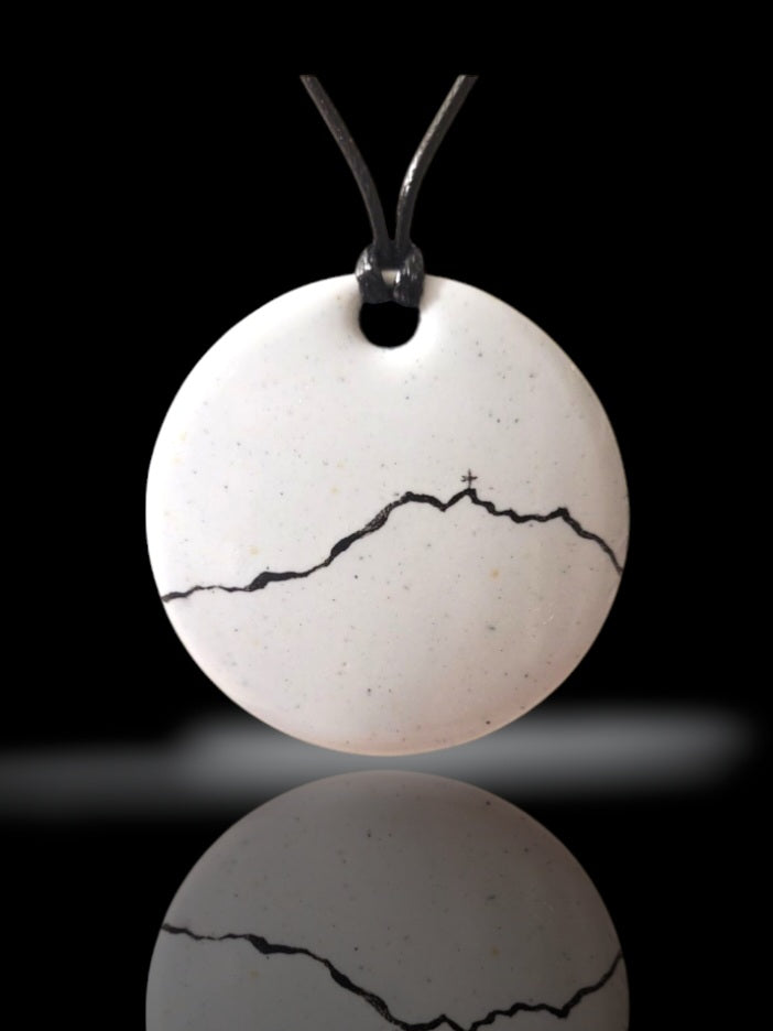 bijou artisanal fait main, grand pendentif en émail blanc avec une ligne noire représentant le profil de la montagne Sainte-Victoire. Création originale Maison calub. Fond noir
