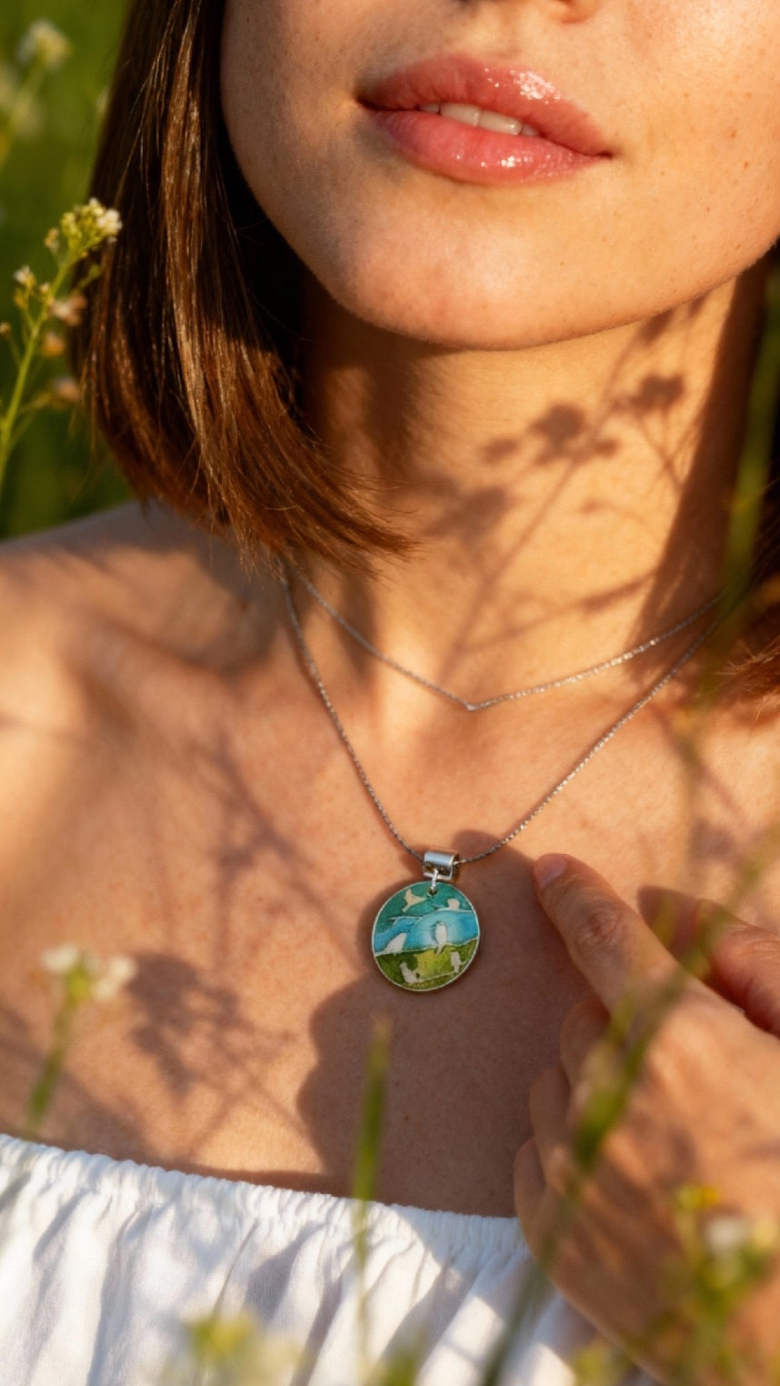 femme portant un pendentif champlevé en émail sur argent fin représentant des oiseaux dans les arbres. Emaux translucides. Bijou artisanal maison Calub les émaux du luberon made in France