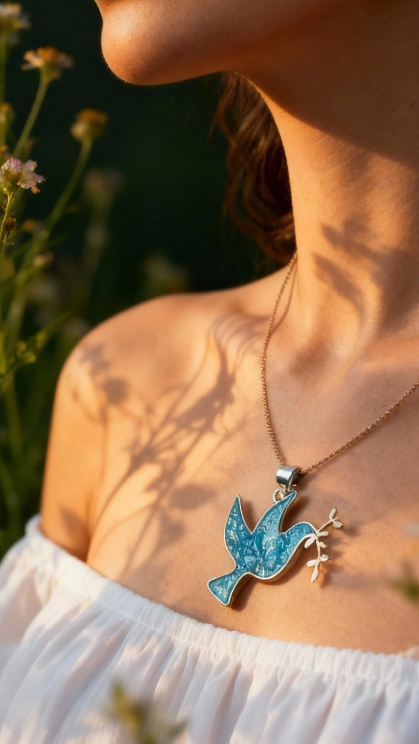 femme portant le Pendentif basse-taille en émail sur argent fin colombe de la paix contemporain. Bijou artisanal réalisé à la main chez maison Calub les émaux du Luberon. Email translucide bleu