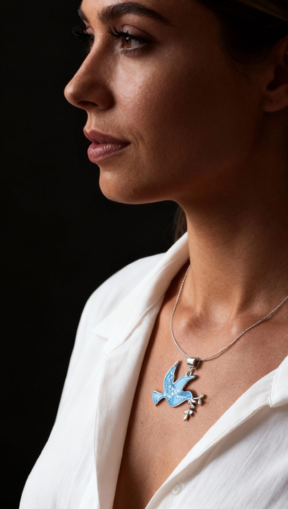 femme portant le Pendentif basse-taille en émail sur argent fin colombe de la paix contemporain. Bijou artisanal réalisé à la main chez maison Calub les émaux du Luberon. Email translucide bleu