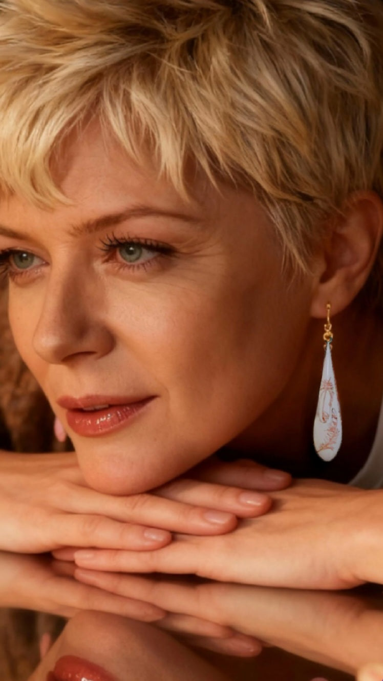 femme portant des boucles d'oreilles gouttes longues en émail sur cuivre aux motifs très fin de plumes . Bijou artisanal maison calub les émaux du Luberon