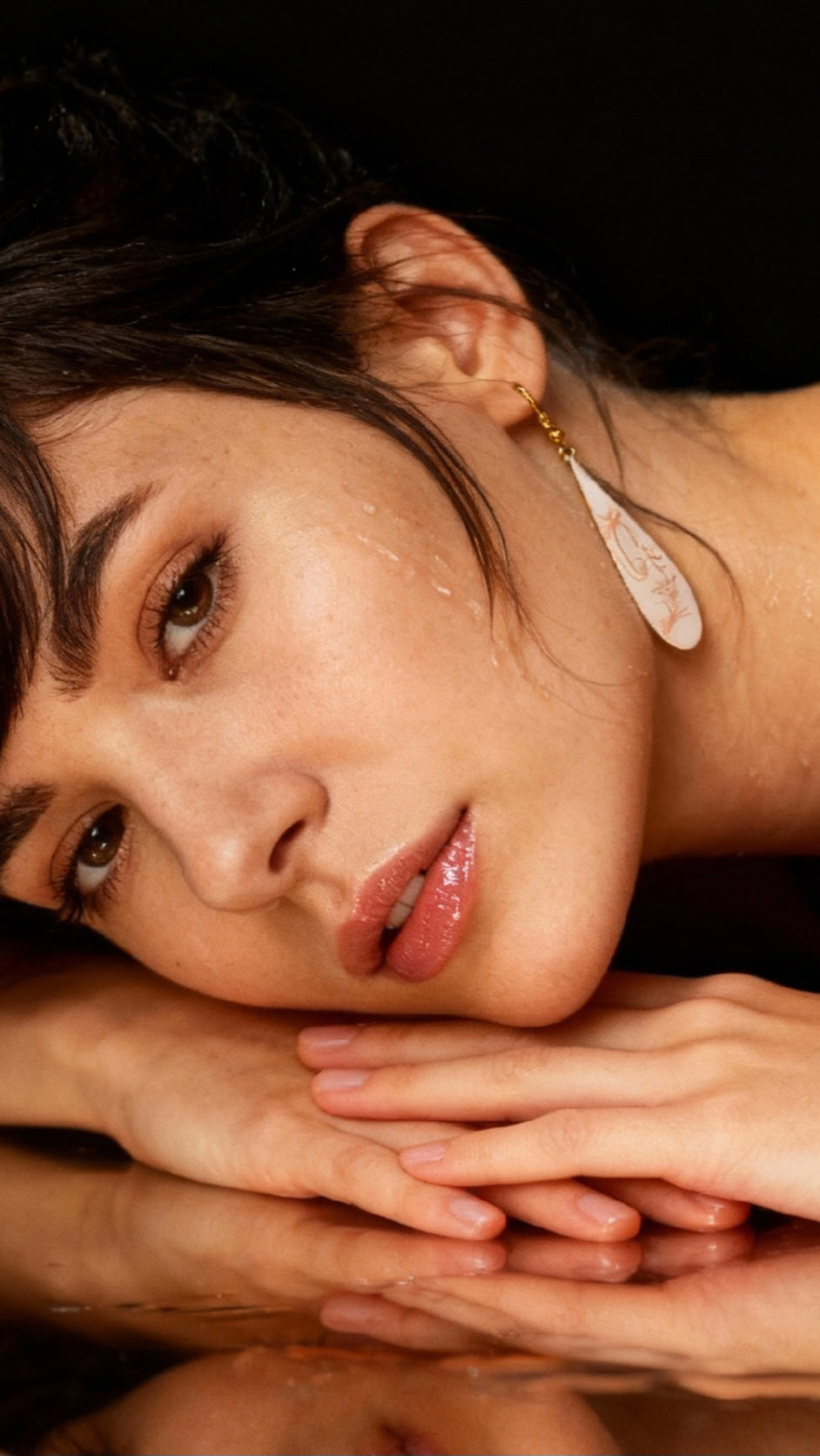 femme avec des boucles d'oreilles gouttes longues en émail sur cuivre aux motifs très fin de plumes . Bijou artisanal maison calub les émaux du Luberon
