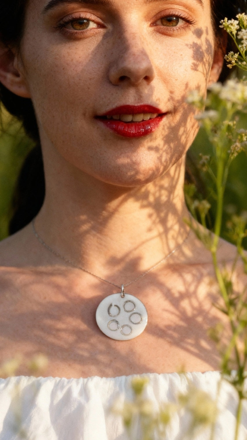 femme portant un pendentif rond en email sur cuivre avec des anneaux en argent incrustés chez maison calub design contemporain - bijou artisanal fait main