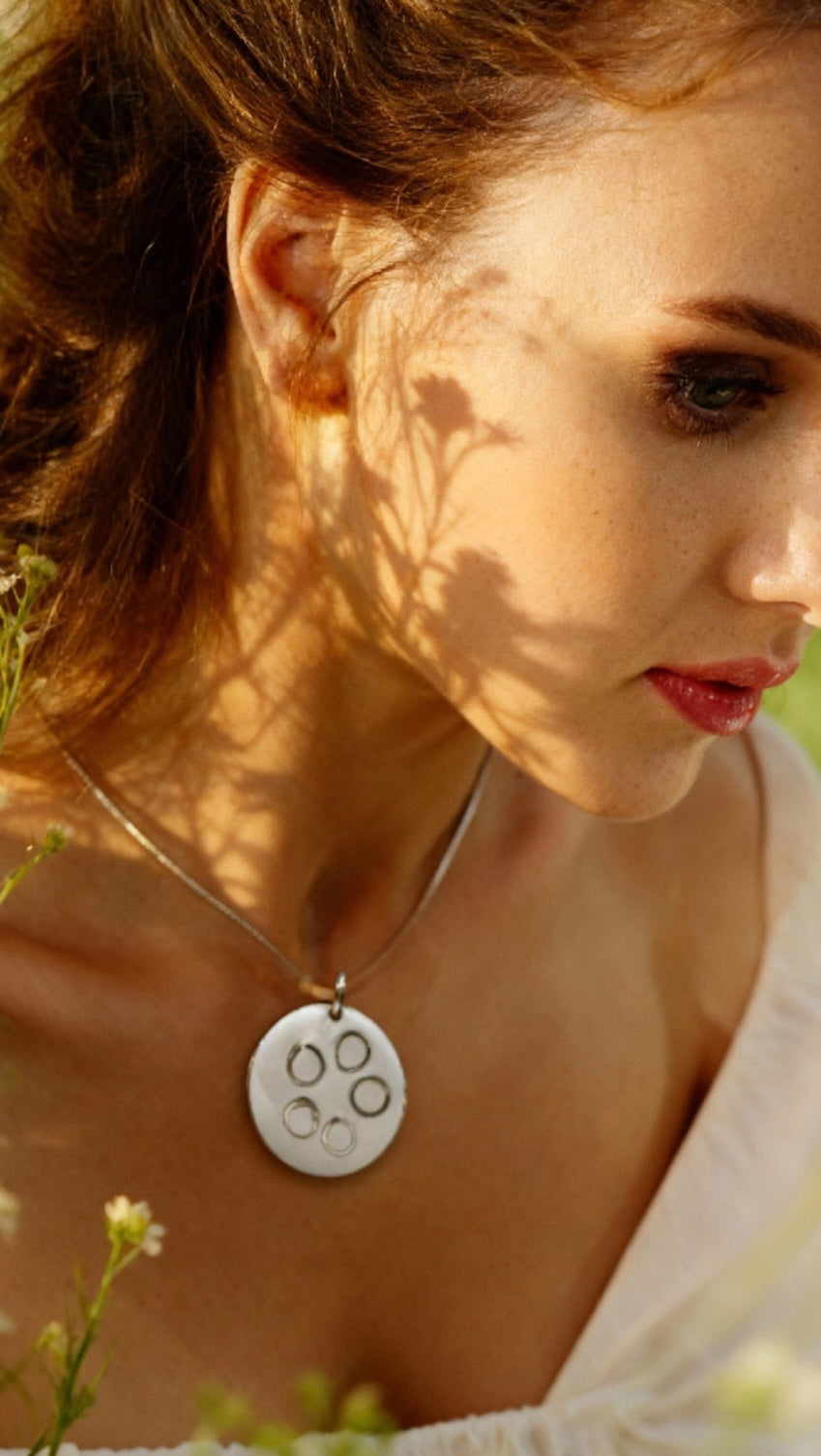 femme portant un pendentif rond en email sur cuivre avec des anneaux en argent incrustés chez maison calub design contemporain - bijou artisanal fait main