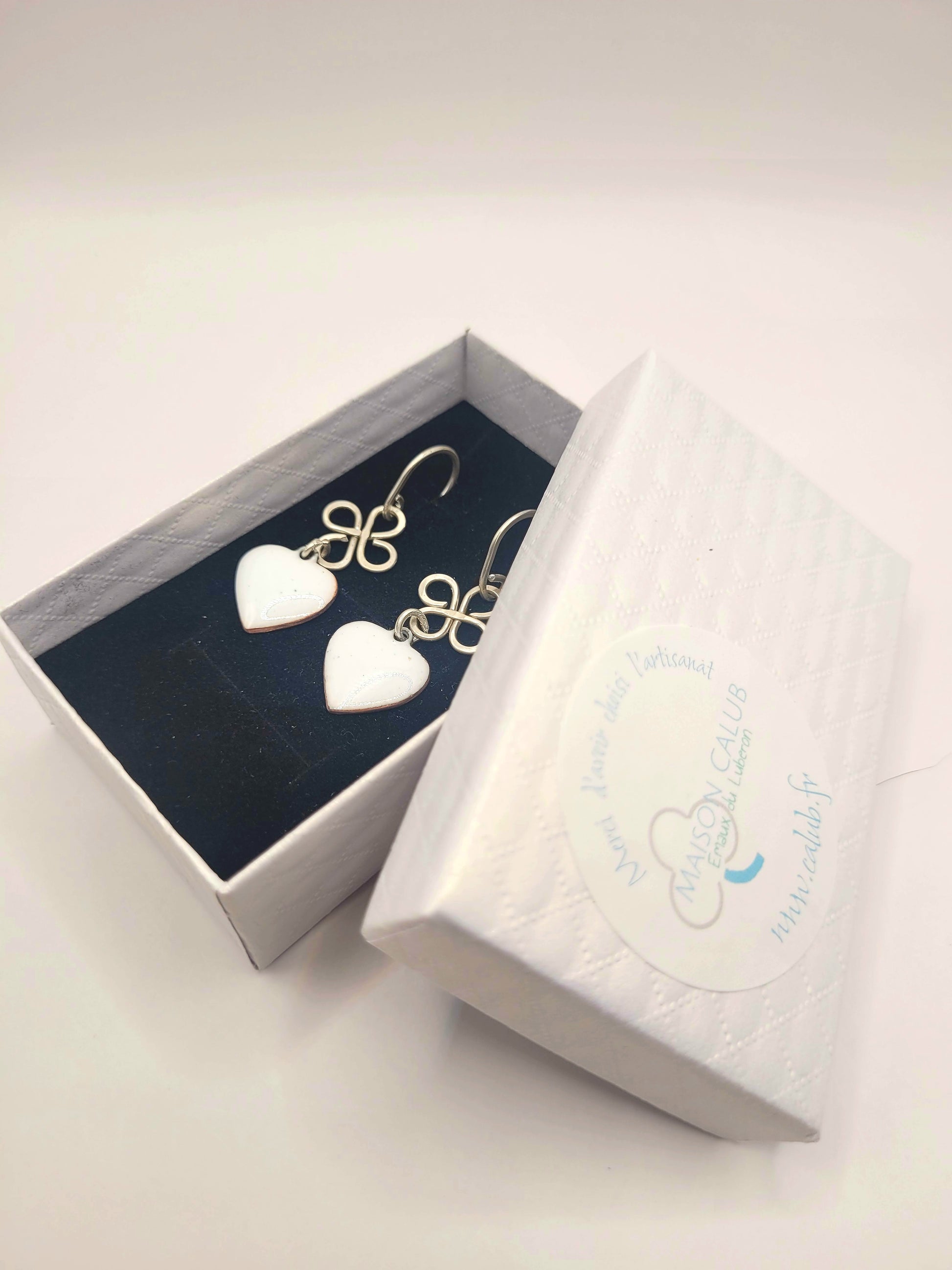 dans une petite boite des boucles d'oreilles coeur en émail  blanc montage sur argent. Création artisanale de maison calub. Emaux opaques