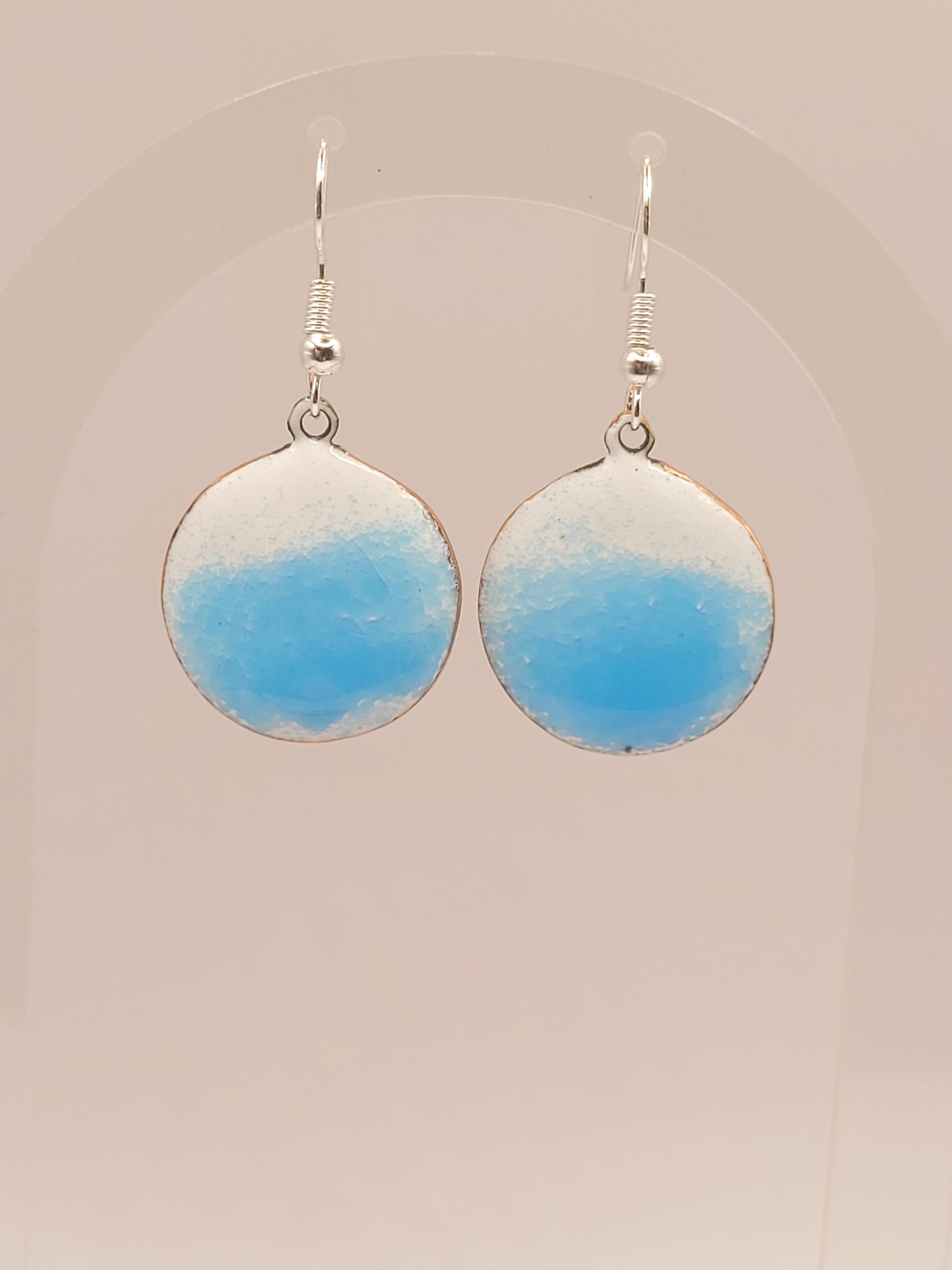 sur un présentoir les boucles d'oreilles rondes oh bleu de maison calub pendant en émail sur cuivre bleu translucide sur fond blanc émaux traditionnels