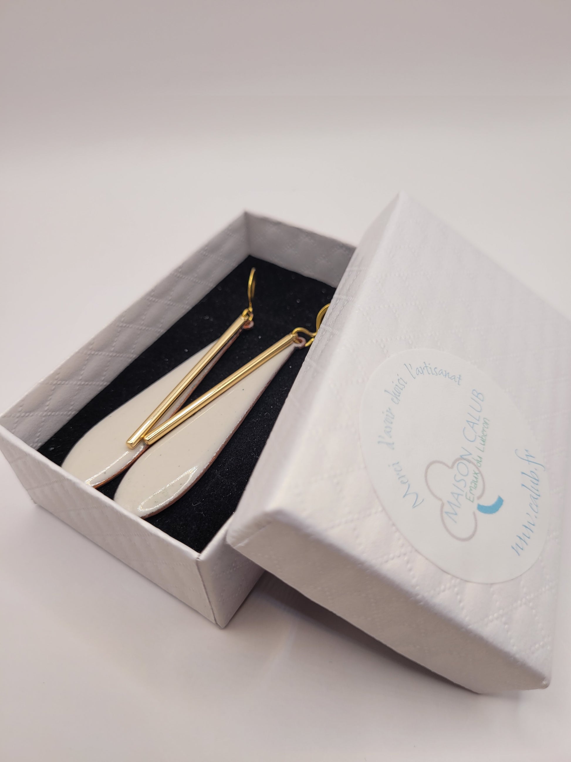 bijou artisanal boucles d'oreilles en email blanc grème et agrémentées d'une longue breloque dorée très simples et légères création maison Calub. Dans sa boite