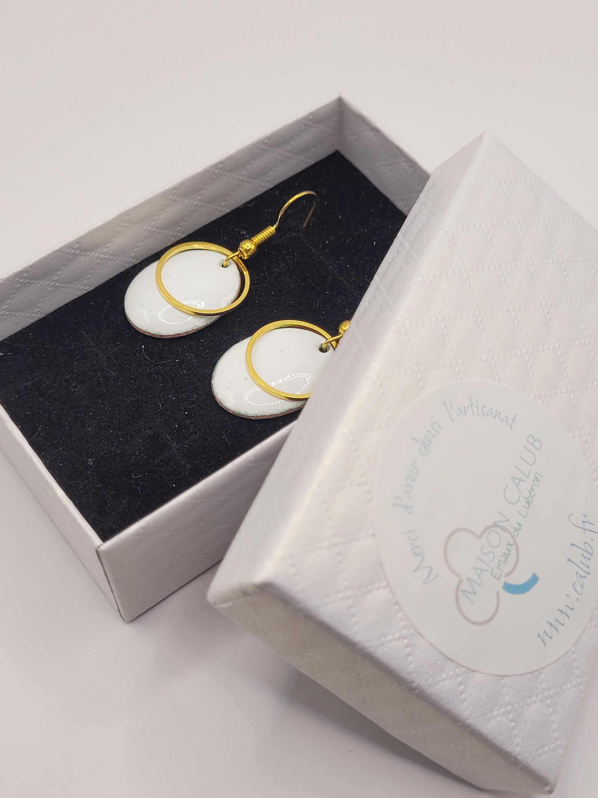 dans une petite boite des boucles d'oreilles blanches en émail avec un anneau doré. Emaux traditionnels fait main chez maison calub. Bijou artisanal