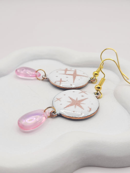 boucles d'oreilles en émail sur cuivre aux motif d'étoiles rosés sur blanc prolongé par une perle de verre goutte. Bijou artisanal fait à la main chez maison calub les emaux du Luberon