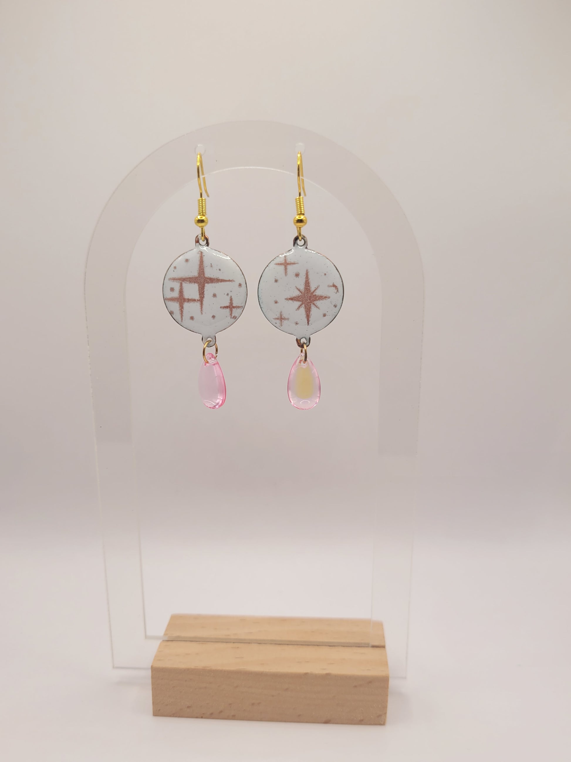 boucles d'oreilles en émail sur cuivre aux motif d'étoiles rosés sur blanc prolongé par une perle de verre goutte. Bijou artisanal fait à la main chez maison calub les emaux du Luberon