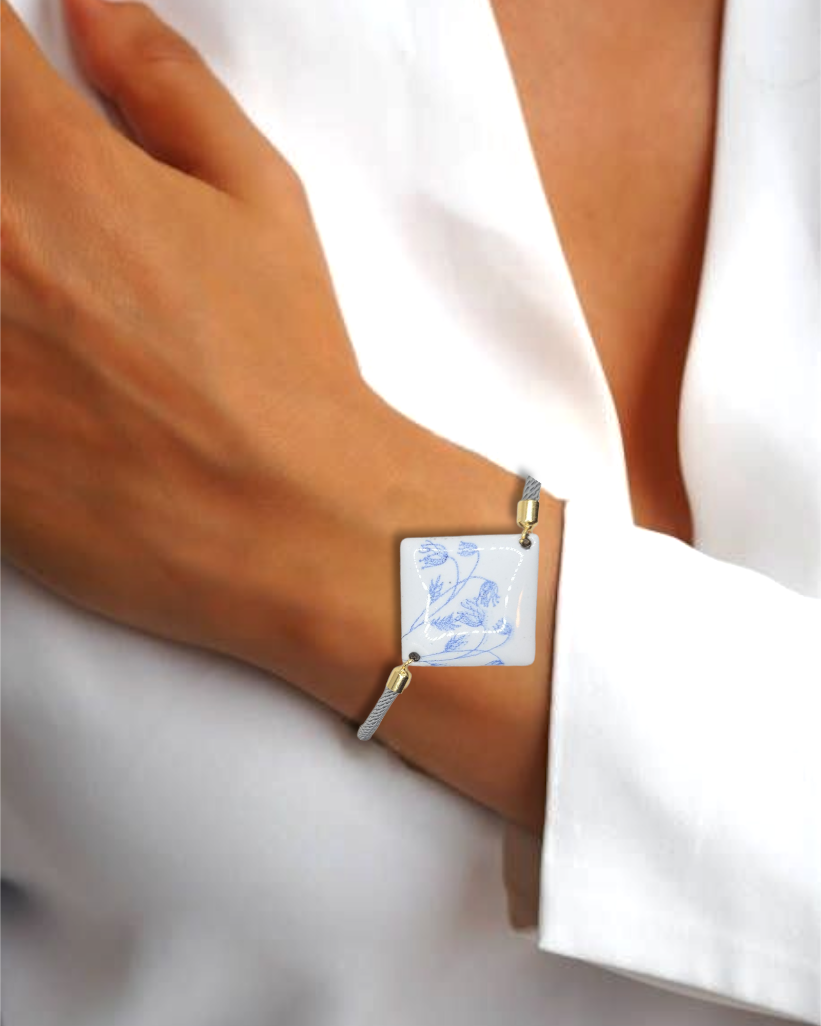 Bracelet cordon gris en émail sur cuivre de forme carrée. Les motifs bleus sur un émail blanc porcelaine dans la collection Les Uniques chez Maison Calub.