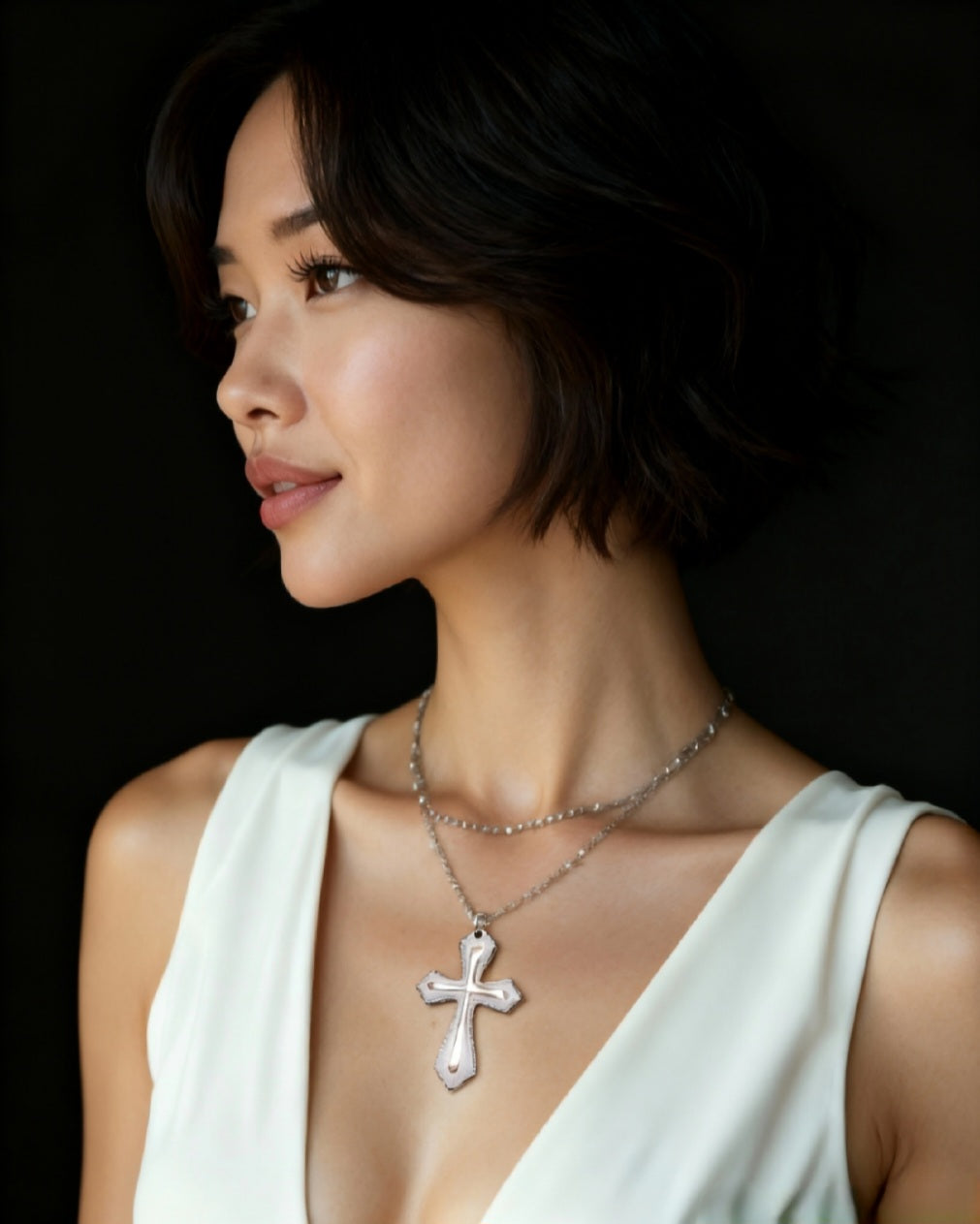 femme portant un bijou artisanal fait main dans les ateliers maison calub. Cest une croix en émail blanche réhaussée par une ligne d'argent