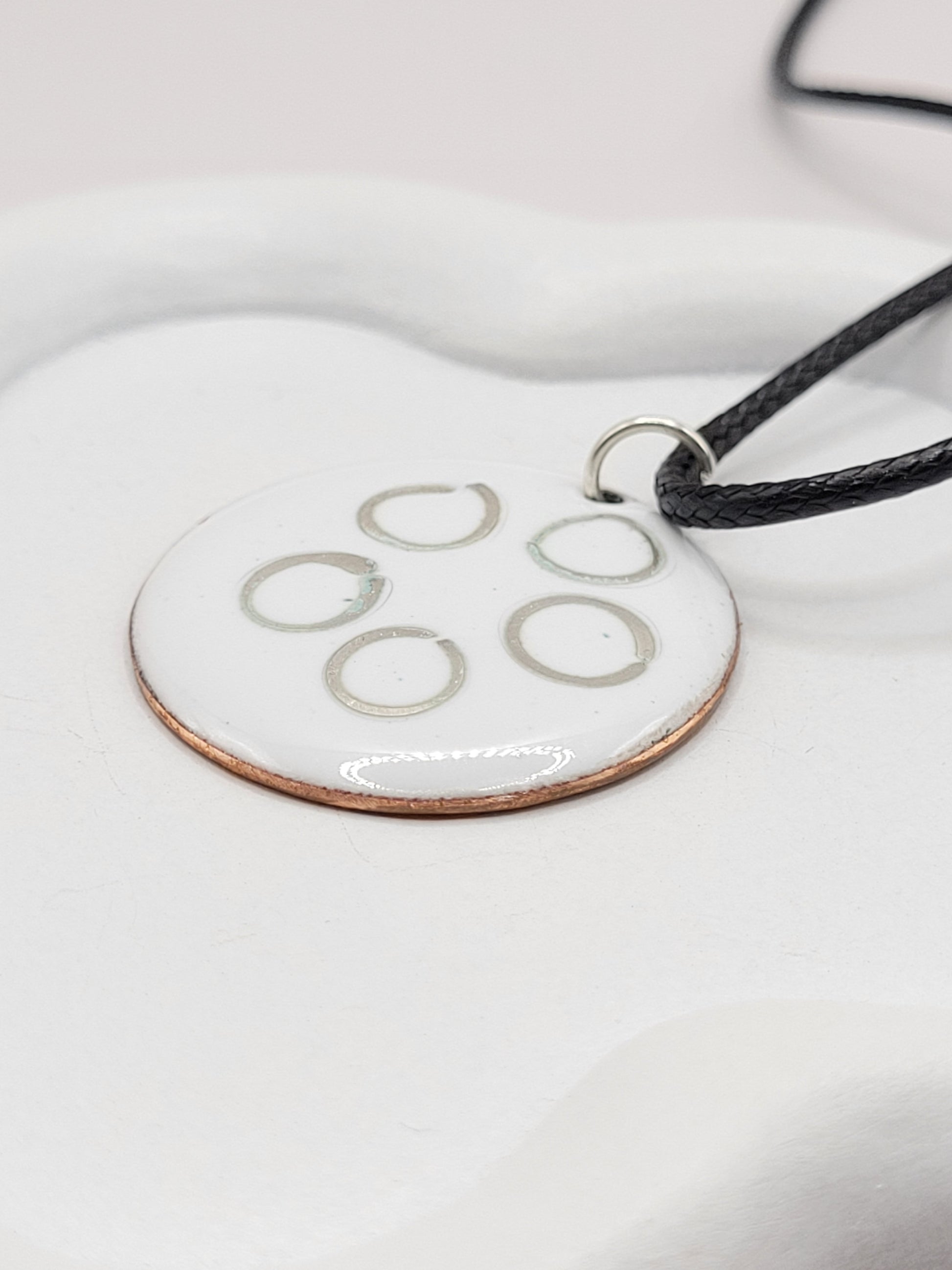 gros plan sur le pendentif rond en email sur cuivre avec des anneaux en argent incrustés chez maison calub design contemporain